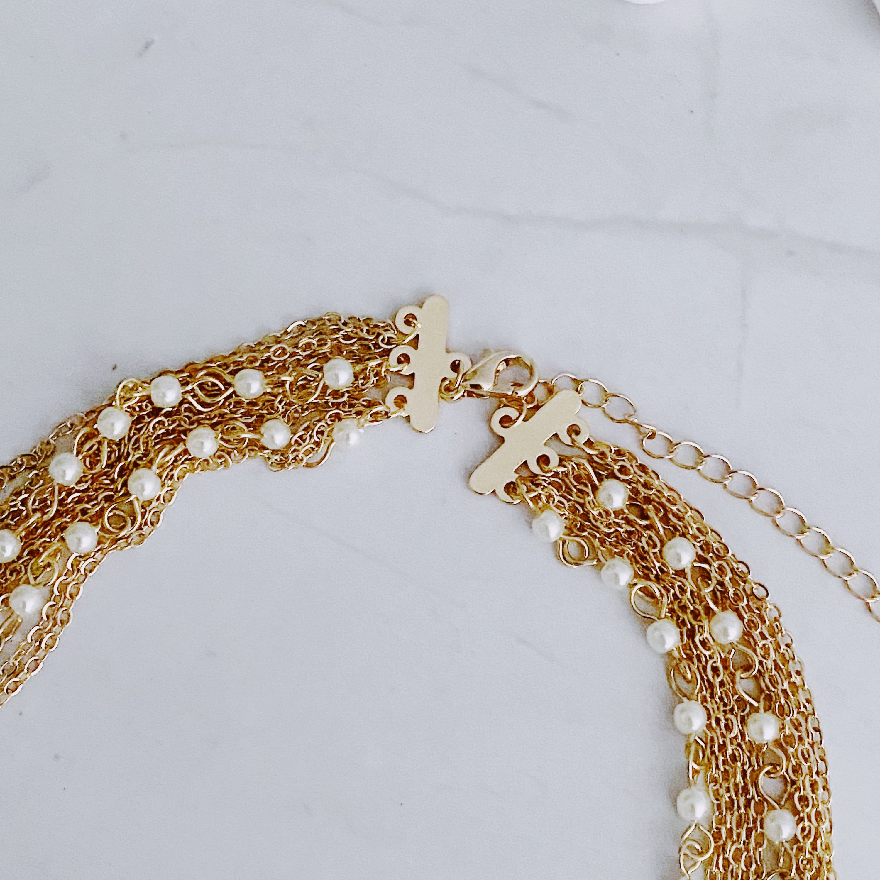 Beautifully Draping Pearl and Chain Necklace featuring 12 layers of gold plated chains and dainty acrylic pearls, elegantly draping around the neck.