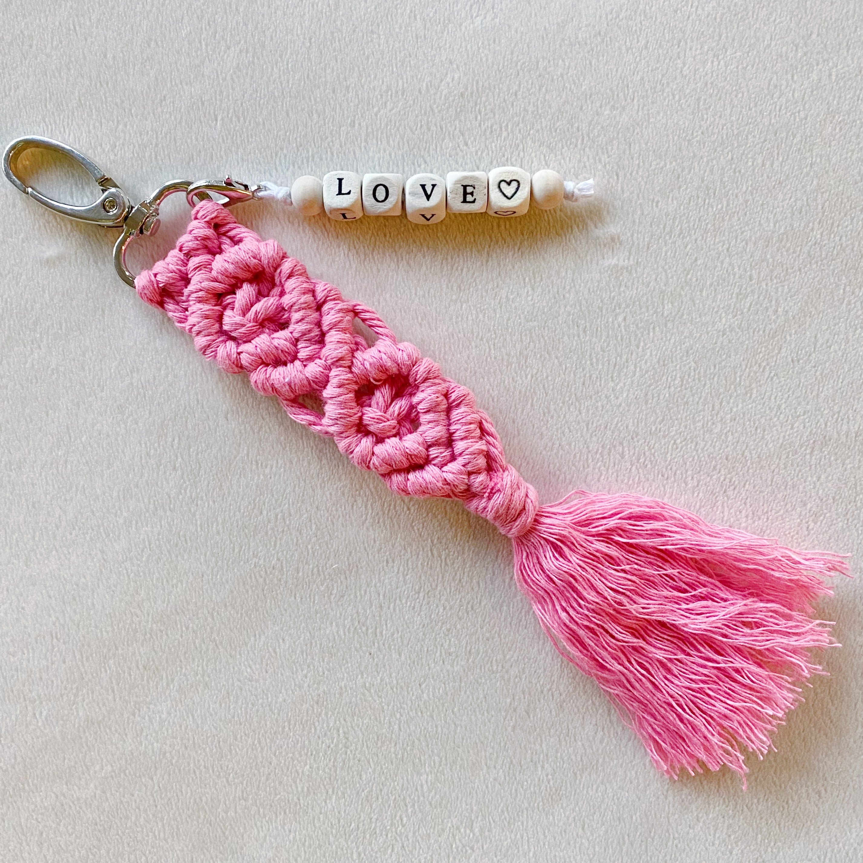 A stylish macrame braided key chain featuring empowering wooden cube beads, showcasing a bohemian design.