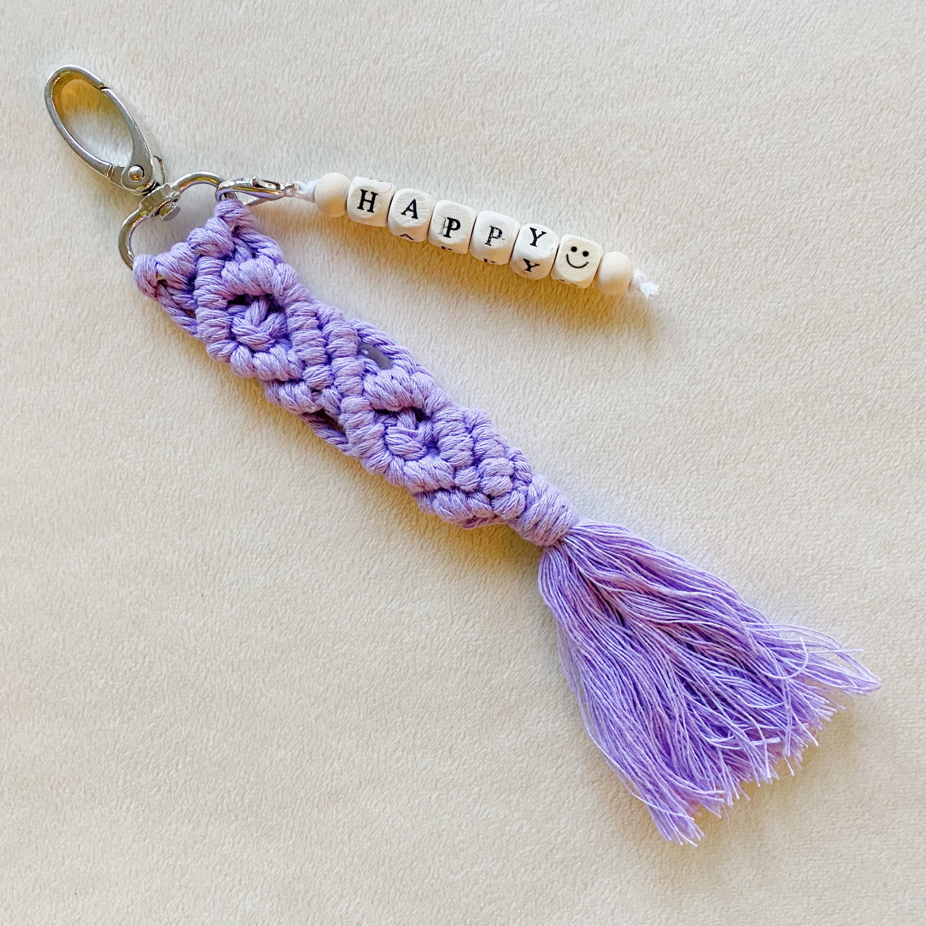 A stylish macrame braided key chain featuring empowering wooden cube beads, showcasing a bohemian design.