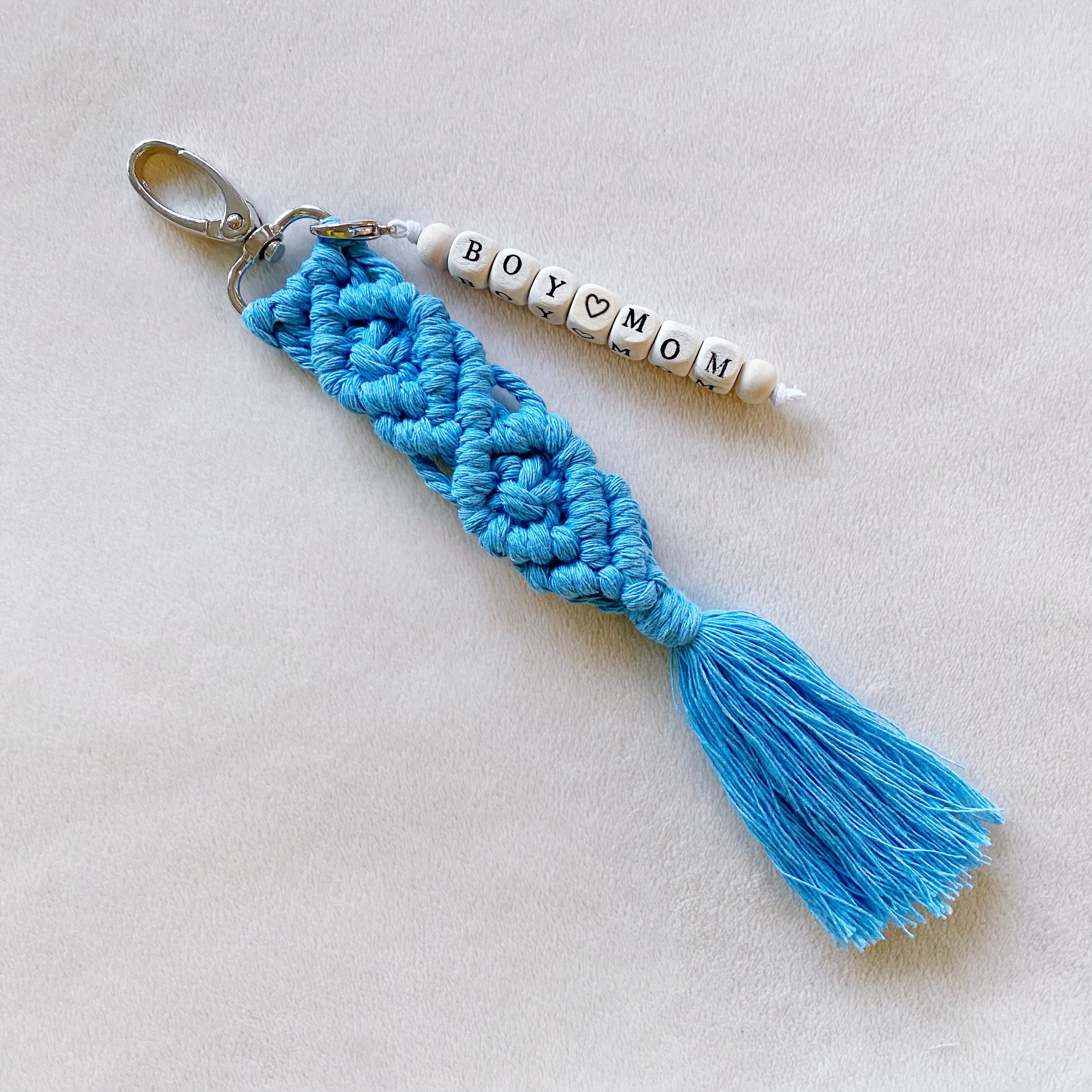 A stylish macrame braided key chain featuring empowering wooden cube beads, showcasing a bohemian design.