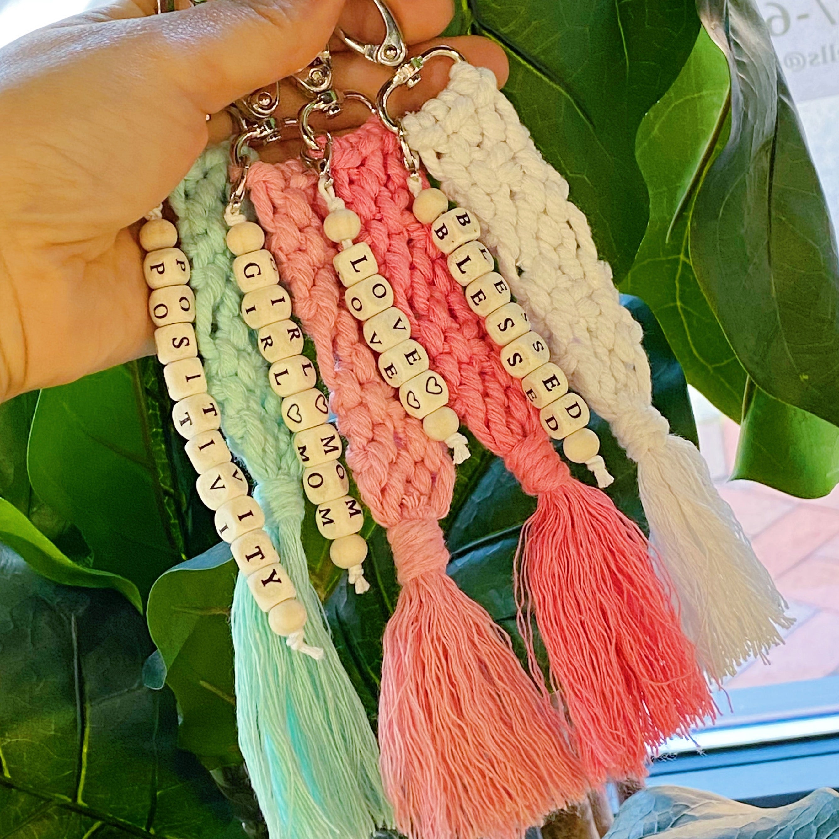 A stylish macrame braided key chain featuring empowering wooden cube beads, showcasing a bohemian design.