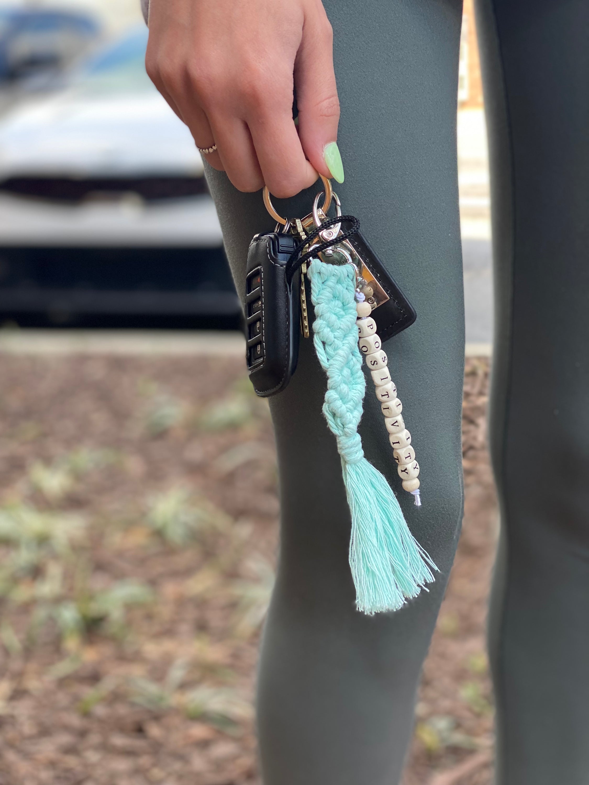 A stylish macrame braided key chain featuring empowering wooden cube beads, showcasing a bohemian design.