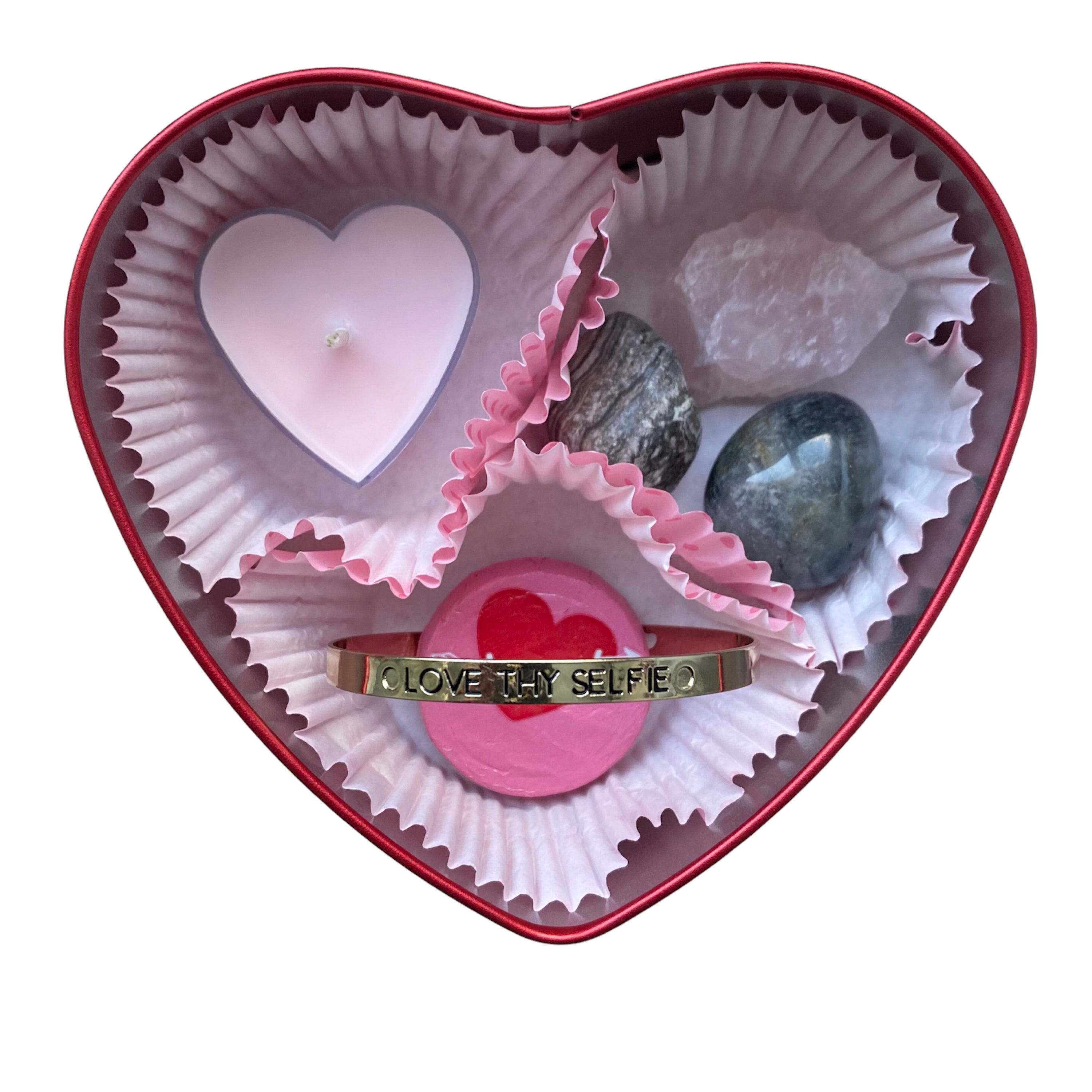 A beautifully arranged heart-shaped gift tin containing crystals, a tea light, a mantra bangle, and a chocolate treat, perfect for gifting.