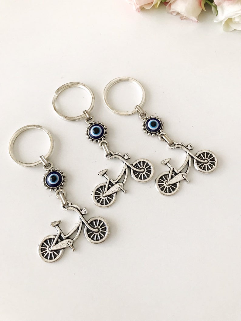 A silver bicycle keychain featuring a blue evil eye charm, symbolizing protection and luck.