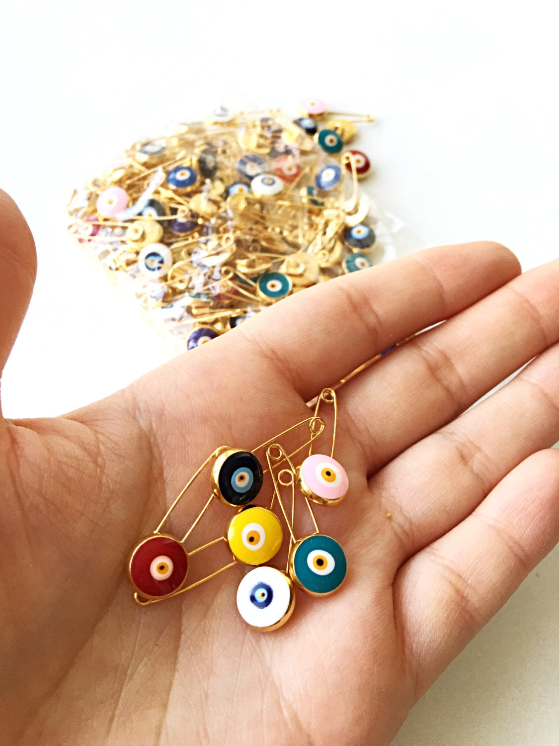 Gold plated lucky evil eye safety pin with big enamel eye, available in multiple colors for baby protection.