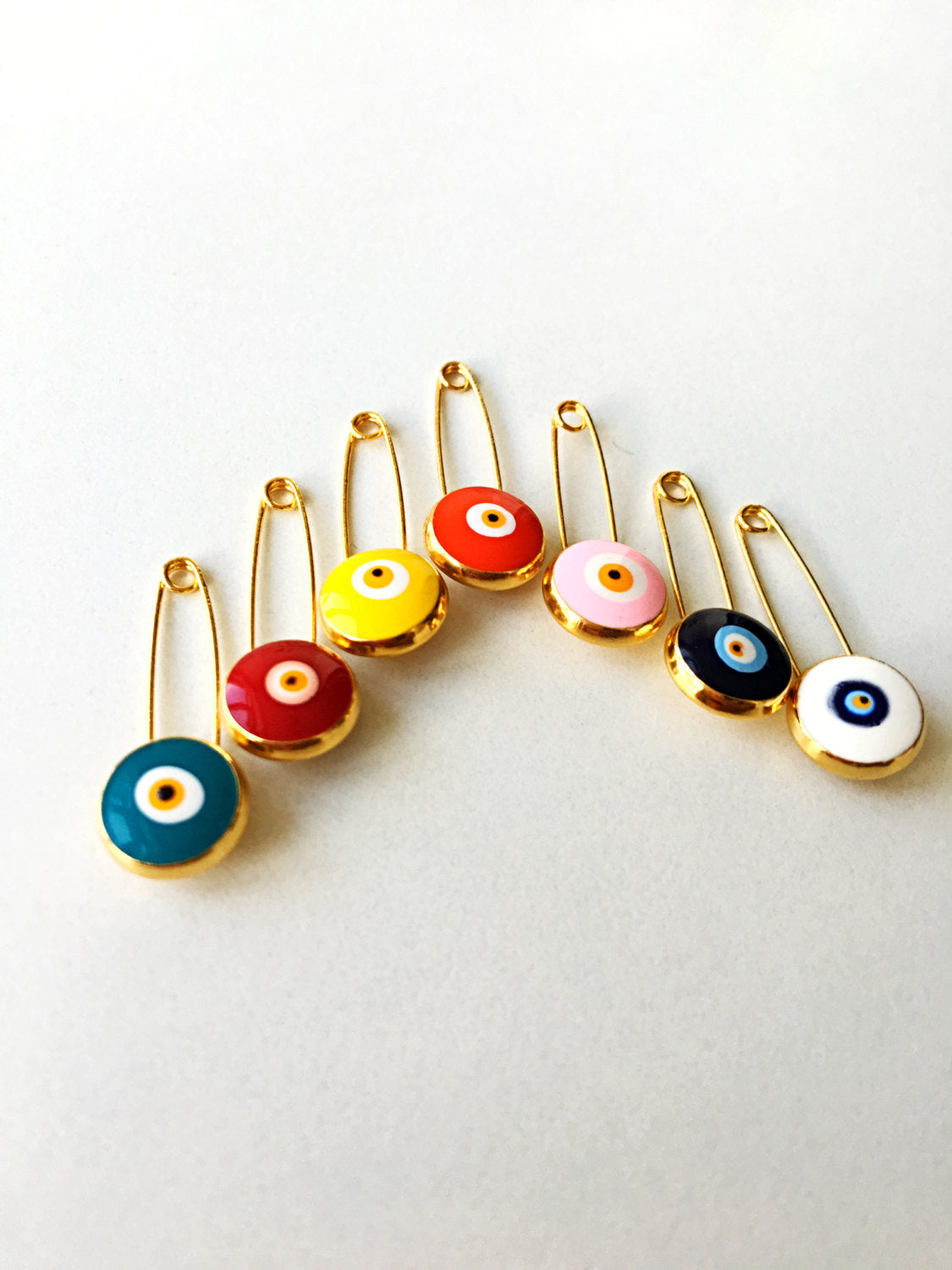 Gold plated lucky evil eye safety pin with big enamel eye, available in multiple colors for baby protection.