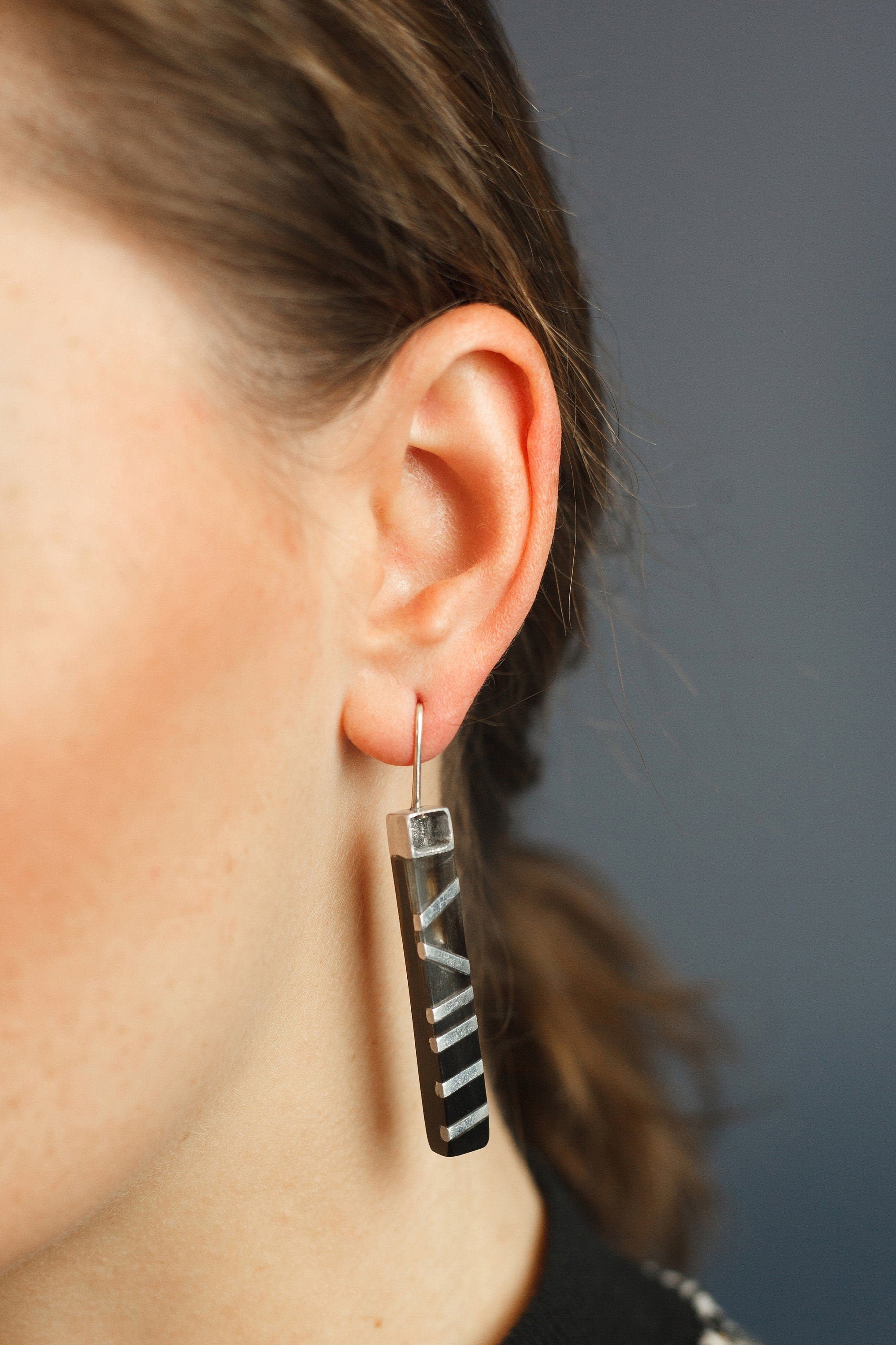 A pair of elegant black horn and aluminum earrings with a 925 sterling silver ear lock, showcasing a unique and stylish design.