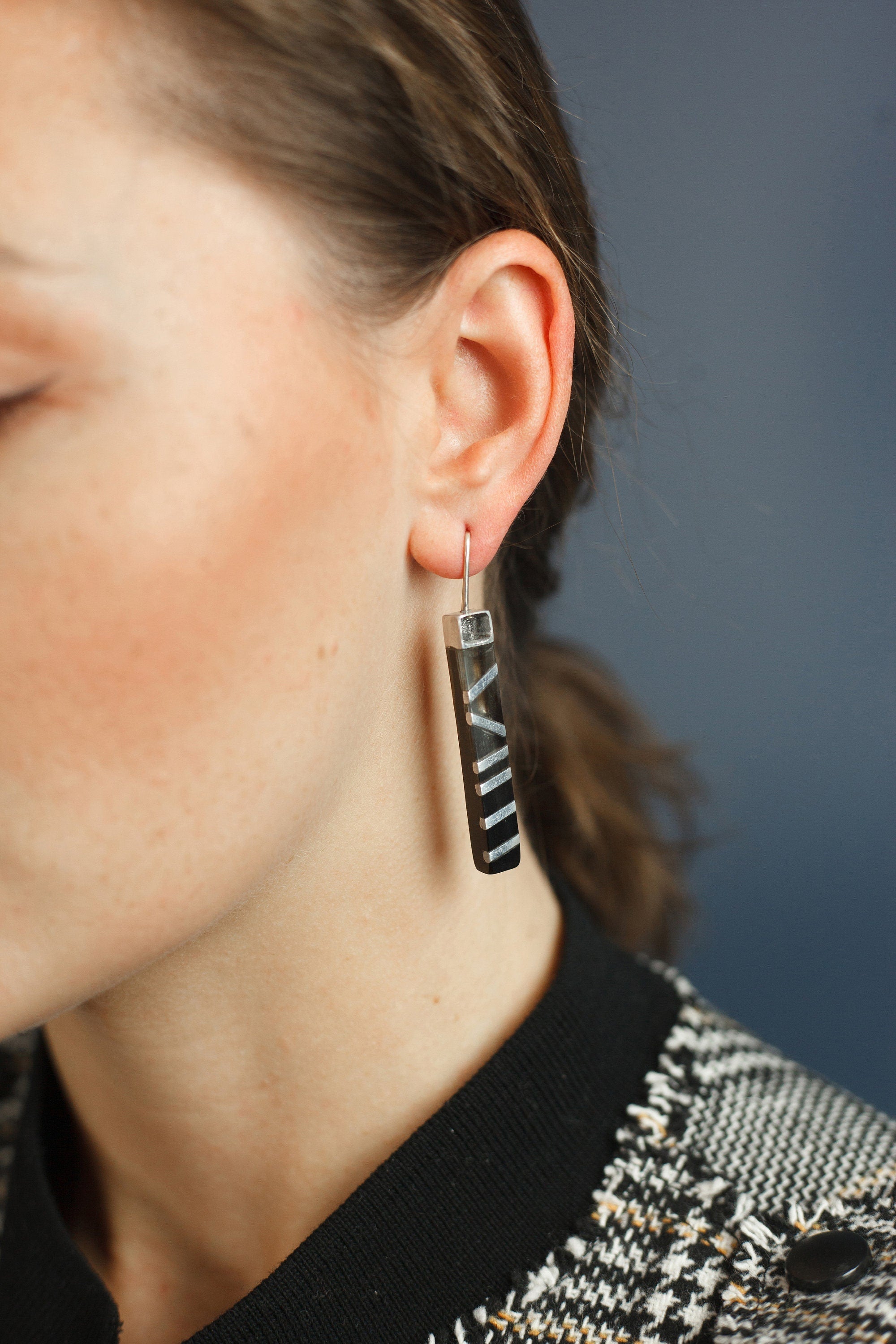 A pair of elegant black horn and aluminum earrings with a 925 sterling silver ear lock, showcasing a unique and stylish design.