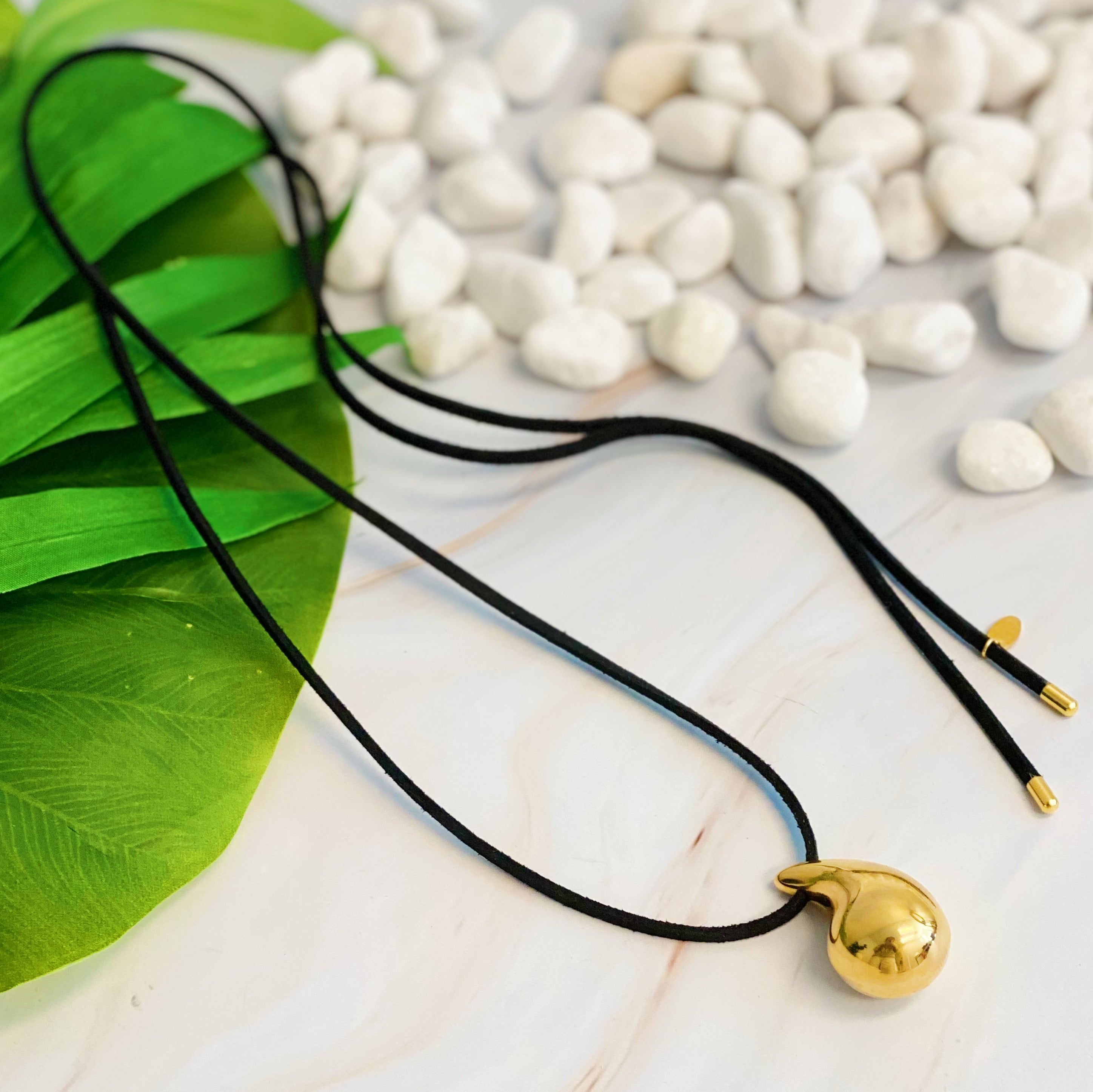 A stylish Black Leather Teardrop Necklace featuring a hollow teardrop pendant on a faux leather cord, elegantly displayed against a neutral background.