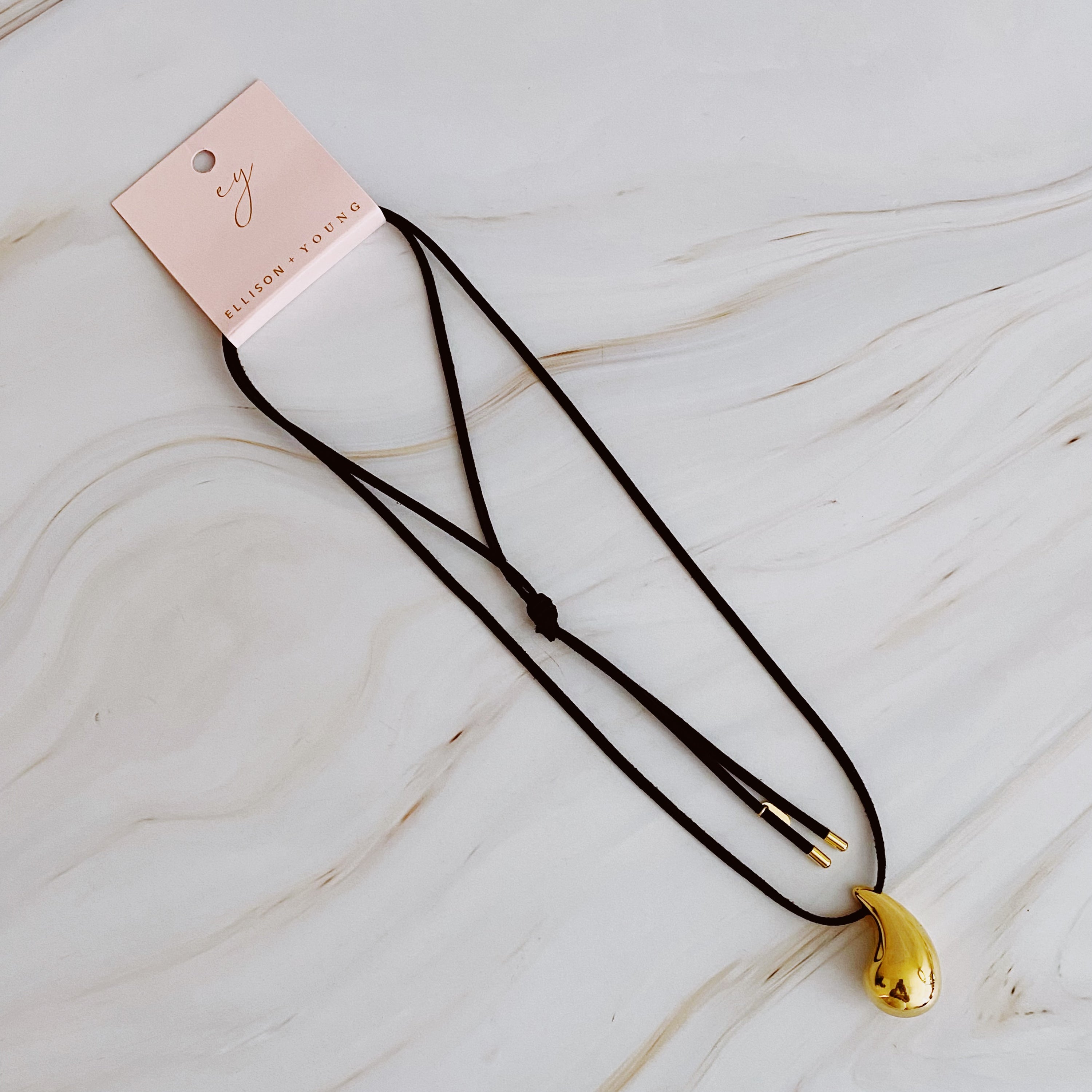 A stylish Black Leather Teardrop Necklace featuring a hollow teardrop pendant on a faux leather cord, elegantly displayed against a neutral background.