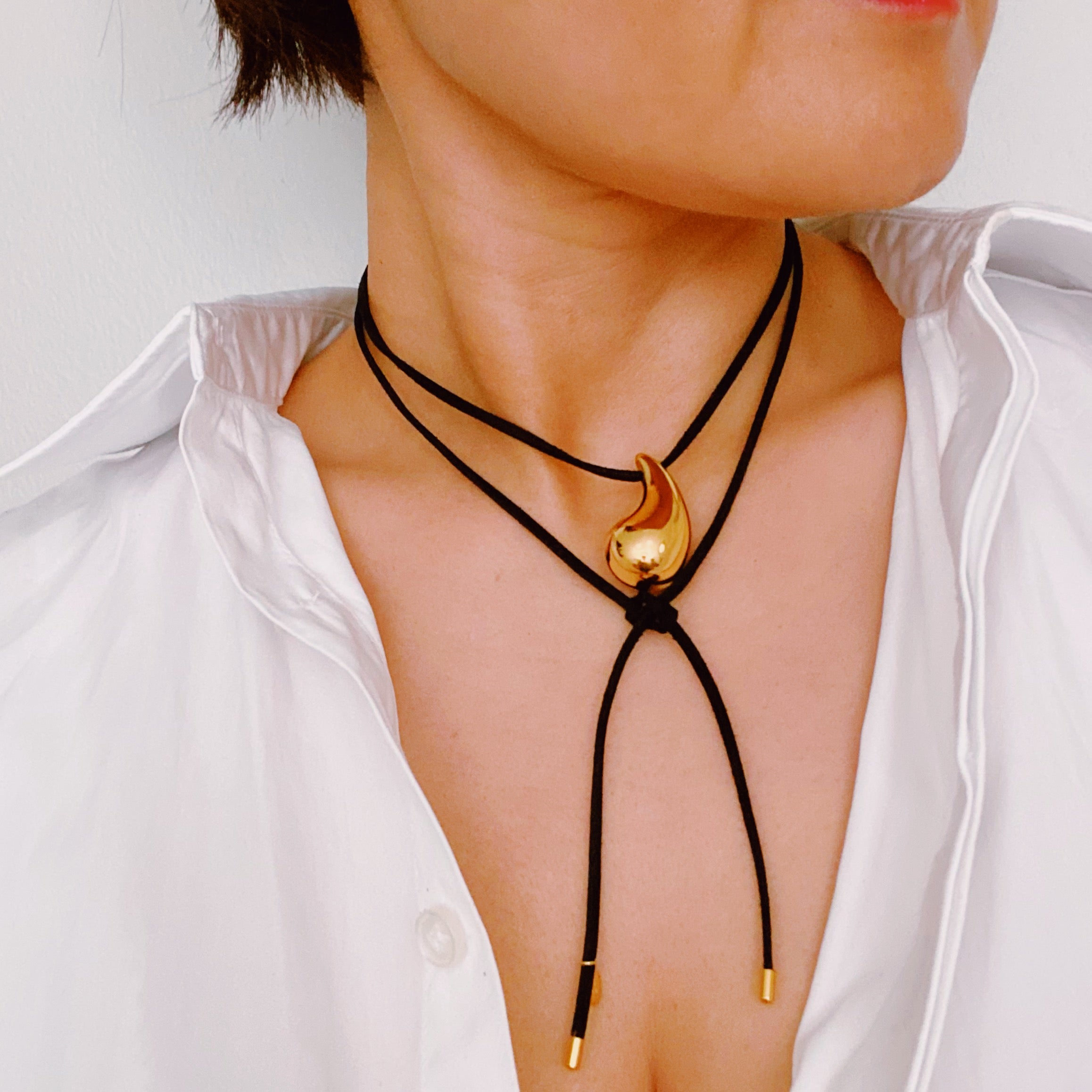 A stylish Black Leather Teardrop Necklace featuring a hollow teardrop pendant on a faux leather cord, elegantly displayed against a neutral background.