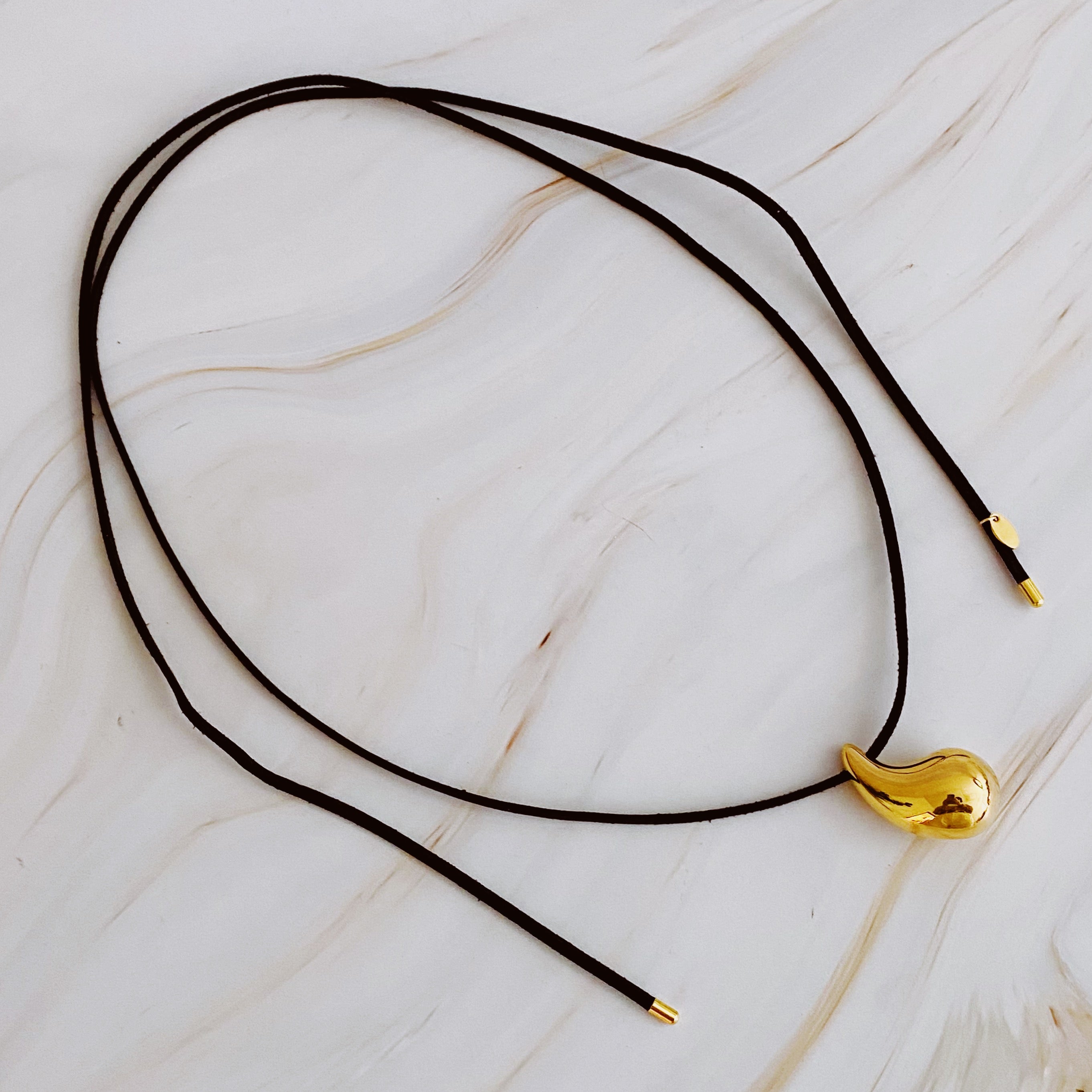 A stylish Black Leather Teardrop Necklace featuring a hollow teardrop pendant on a faux leather cord, elegantly displayed against a neutral background.