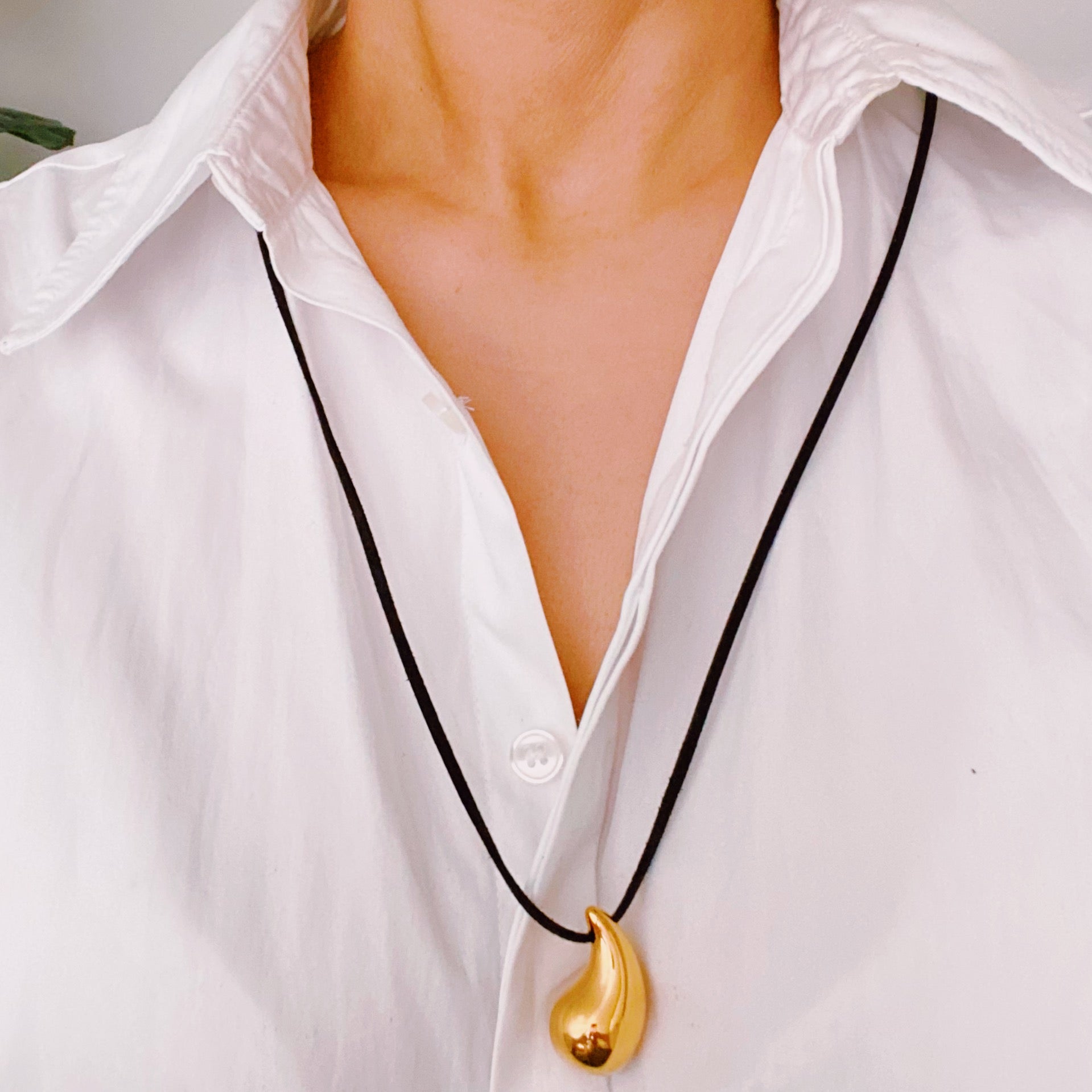 A stylish Black Leather Teardrop Necklace featuring a hollow teardrop pendant on a faux leather cord, elegantly displayed against a neutral background.