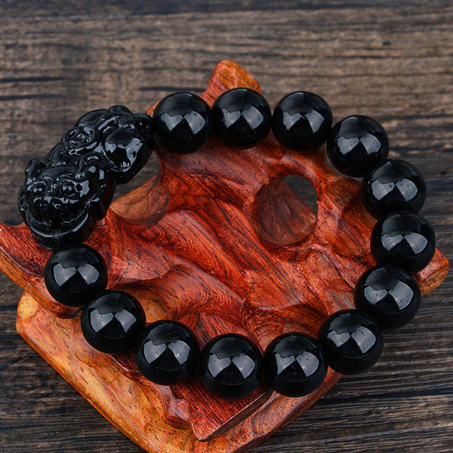 A stylish Black Obsidian Pi Xiu Bracelet featuring 12 mm beads and a Pi Xiu amulet, symbolizing wealth and protection.