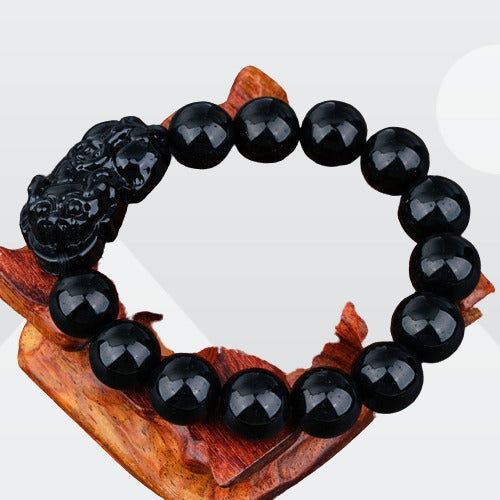 A stylish Black Obsidian Pi Xiu Bracelet featuring 12 mm beads and a Pi Xiu amulet, symbolizing wealth and protection.