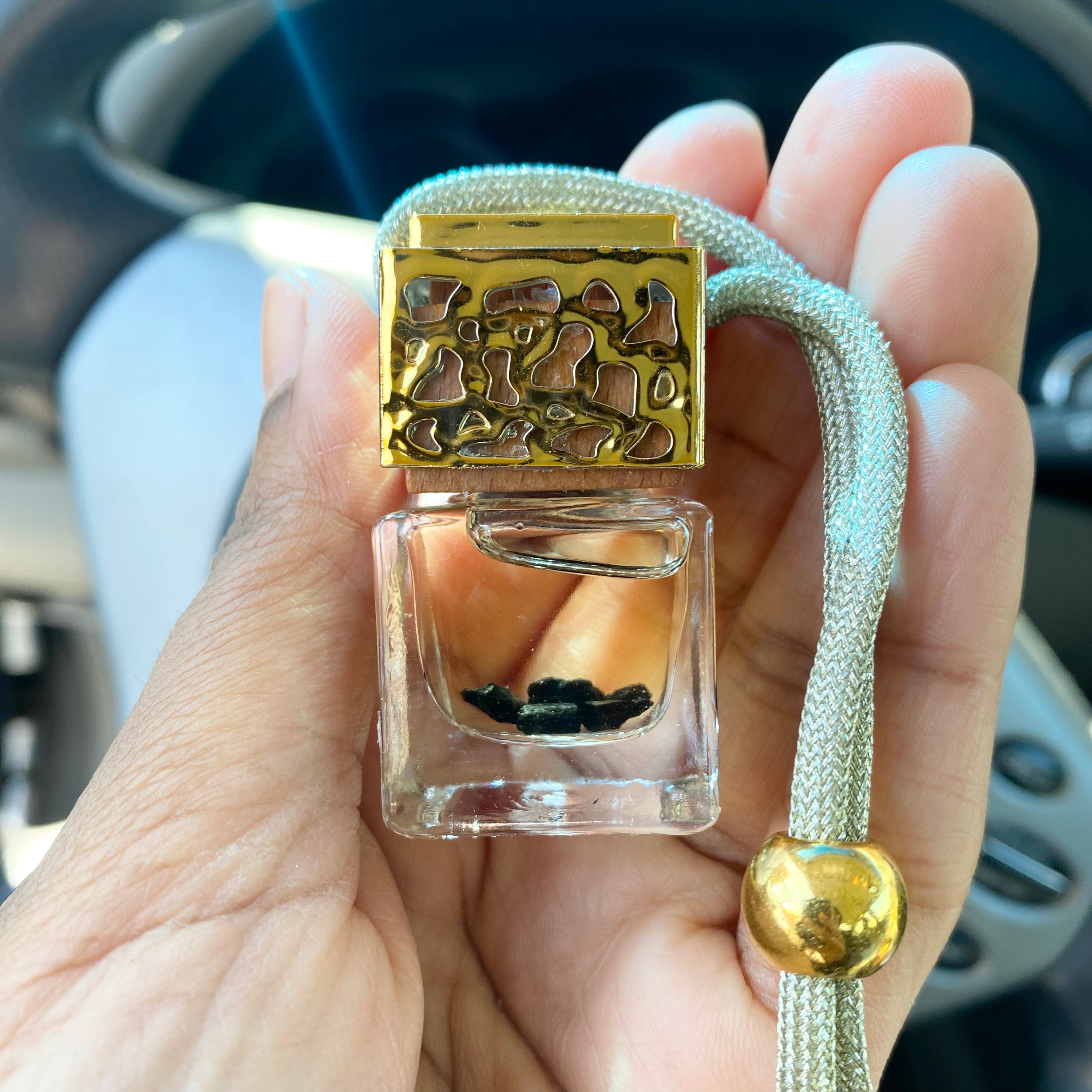 A luxurious Black Tourmaline Car Diffuser featuring black tourmaline chips, available in gold and silver finishes, designed to repel negative energy.