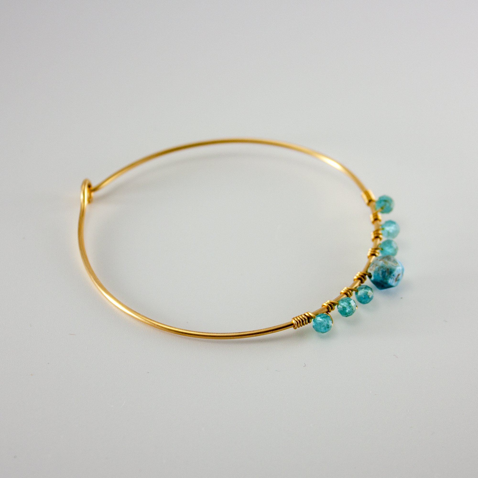 A beautiful blue apatite beaded gold bangle featuring 4mm and 8mm apatite stones, set in a gold-plated brass design.