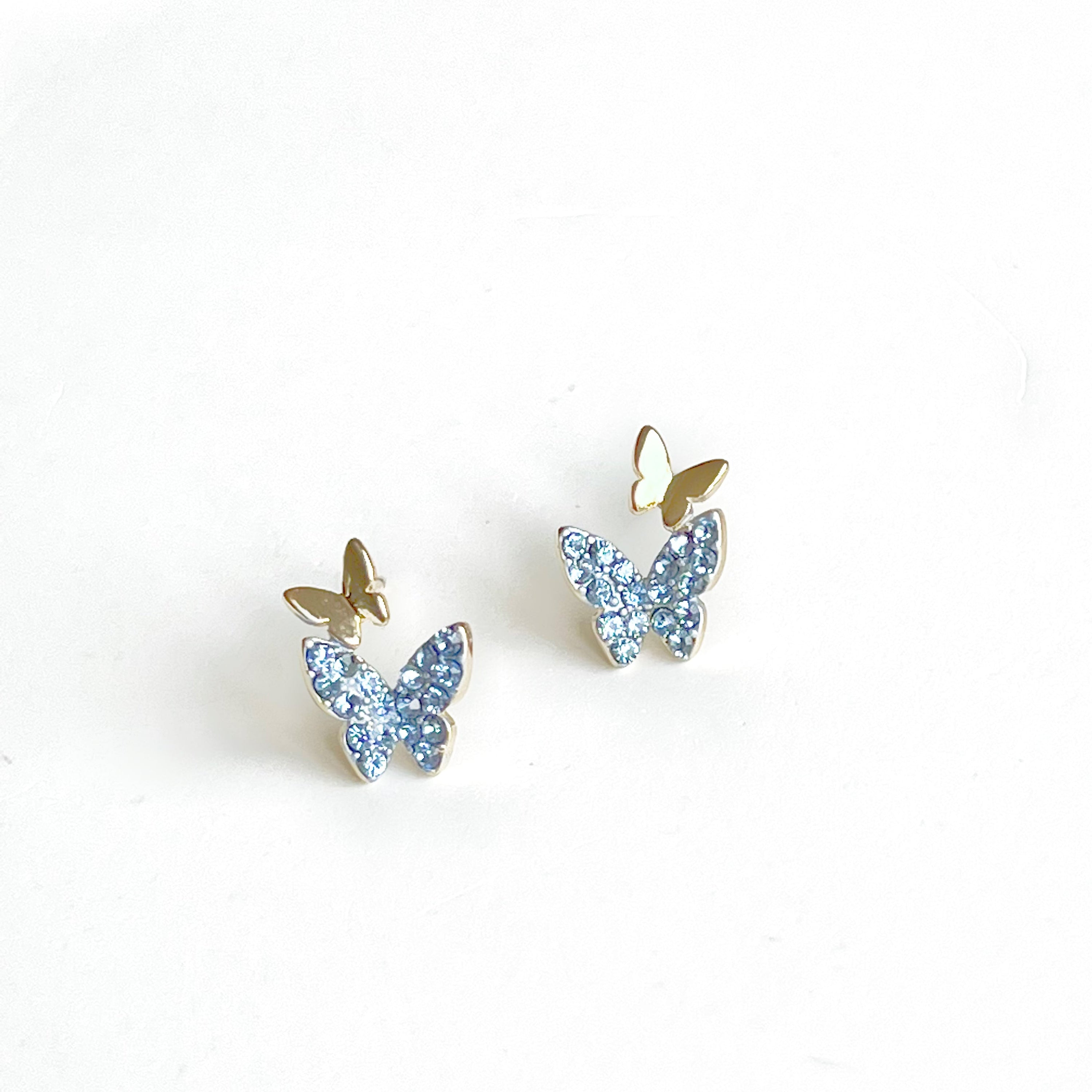 A pair of elegant blue crystal butterfly earrings made from gold-plated sterling silver and bronze, featuring shimmering blue zircon stones.