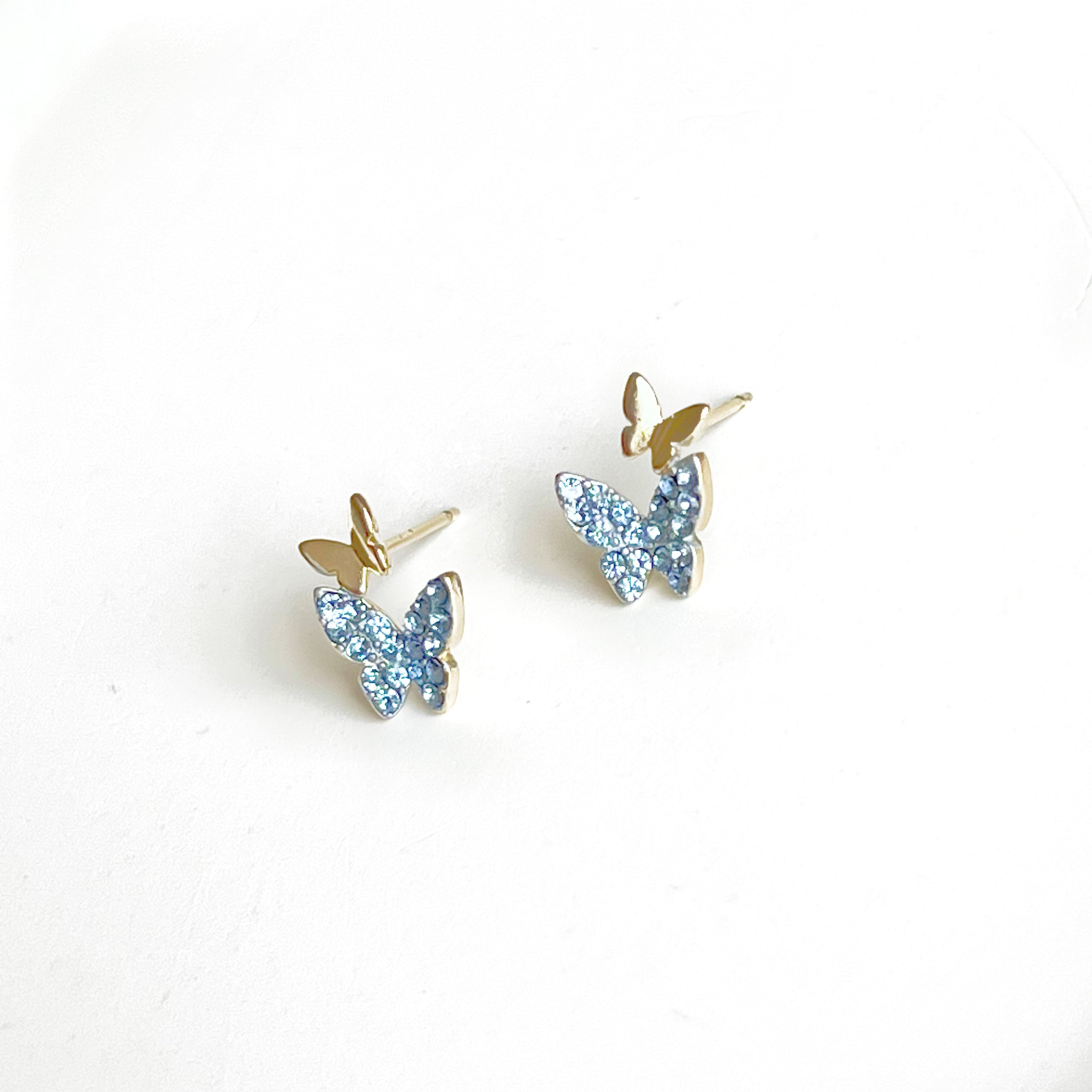 A pair of elegant blue crystal butterfly earrings made from gold-plated sterling silver and bronze, featuring shimmering blue zircon stones.