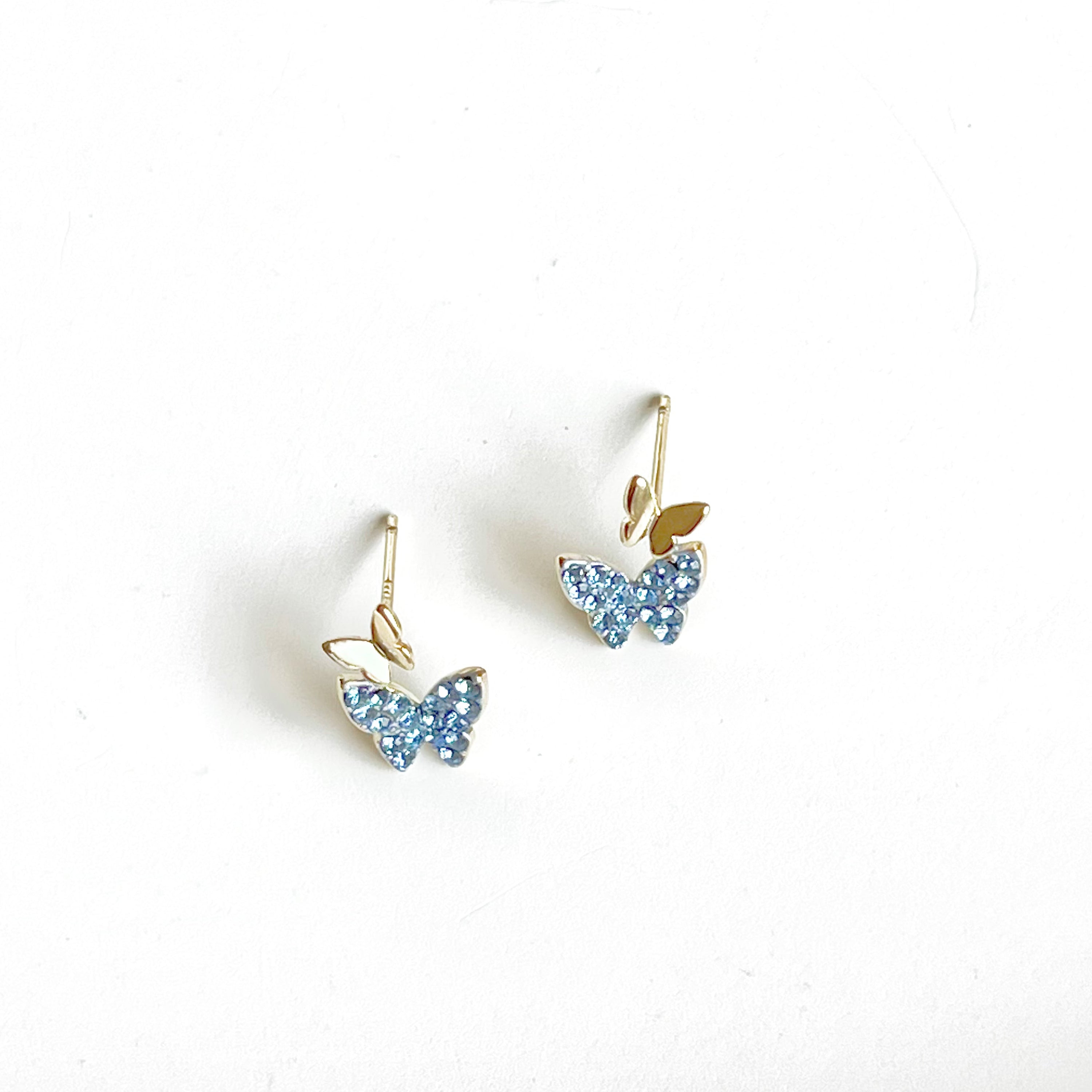 A pair of elegant blue crystal butterfly earrings made from gold-plated sterling silver and bronze, featuring shimmering blue zircon stones.