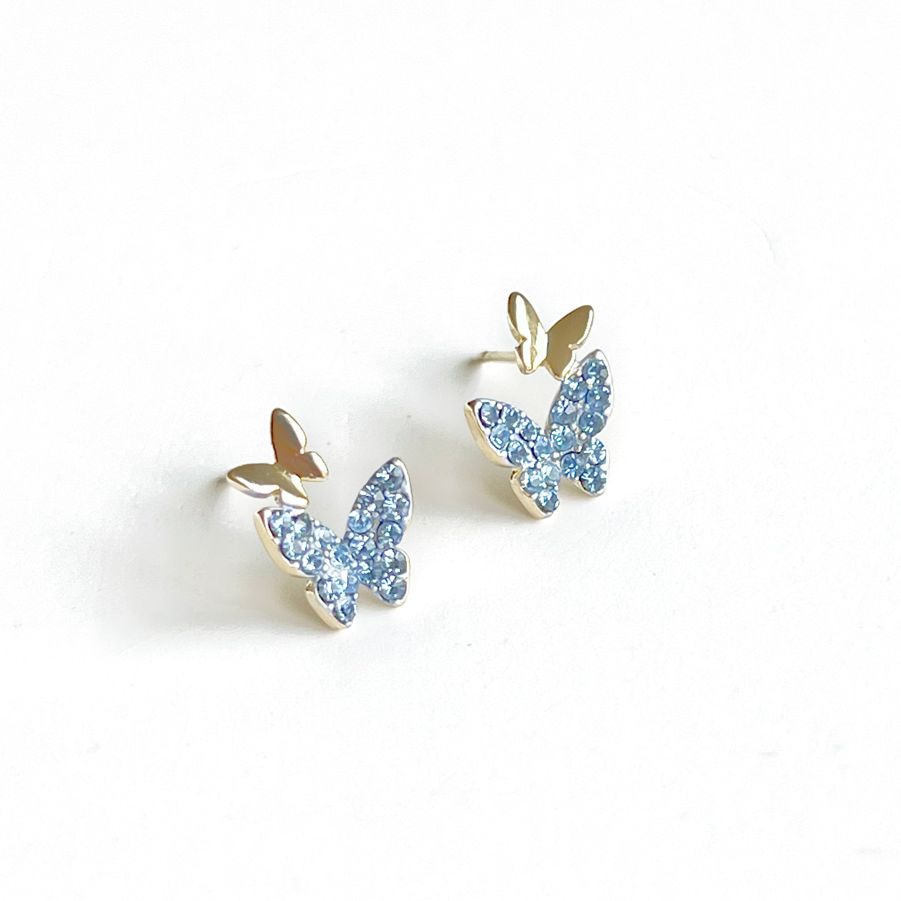 A pair of elegant blue crystal butterfly earrings made from gold-plated sterling silver and bronze, featuring shimmering blue zircon stones.