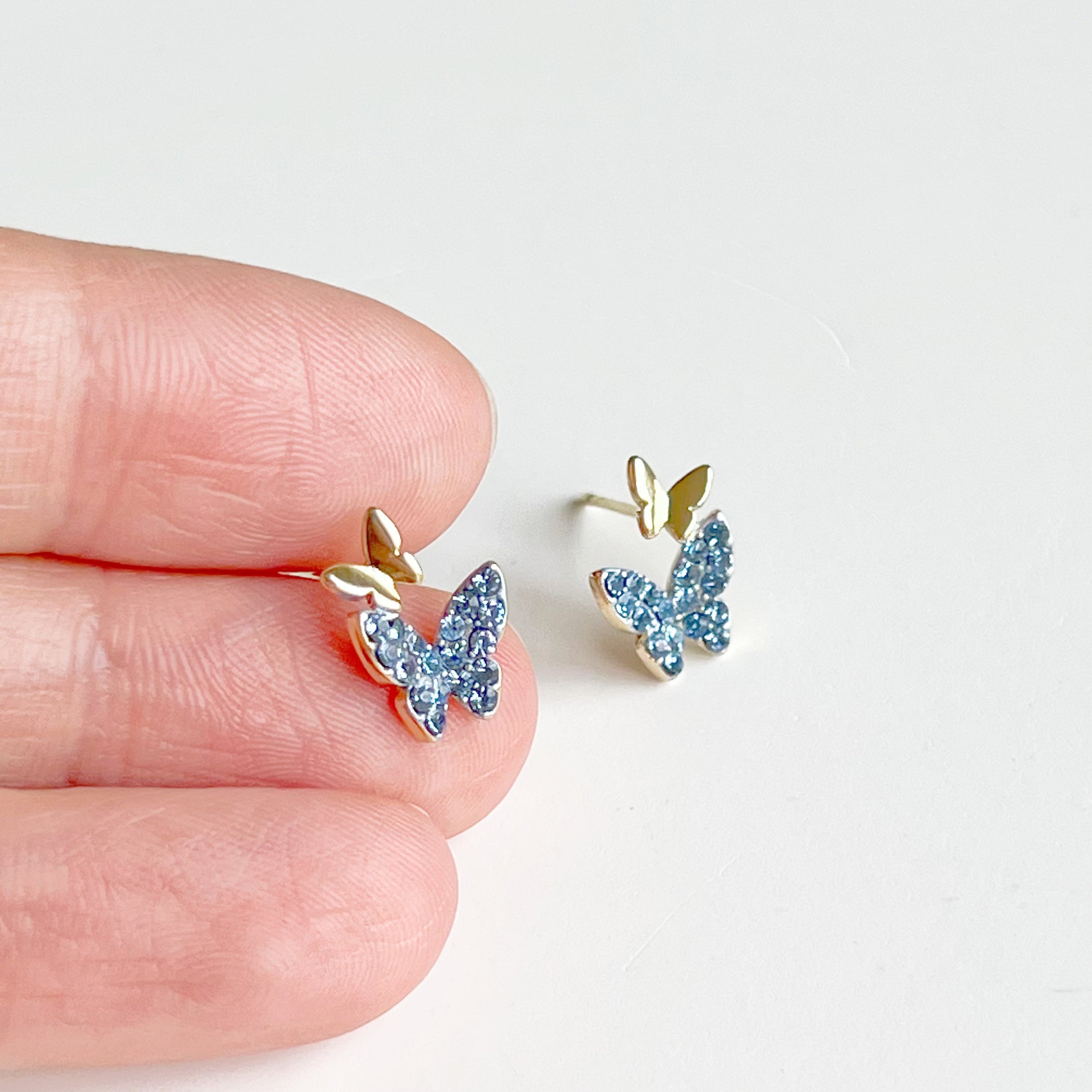 A pair of elegant blue crystal butterfly earrings made from gold-plated sterling silver and bronze, featuring shimmering blue zircon stones.