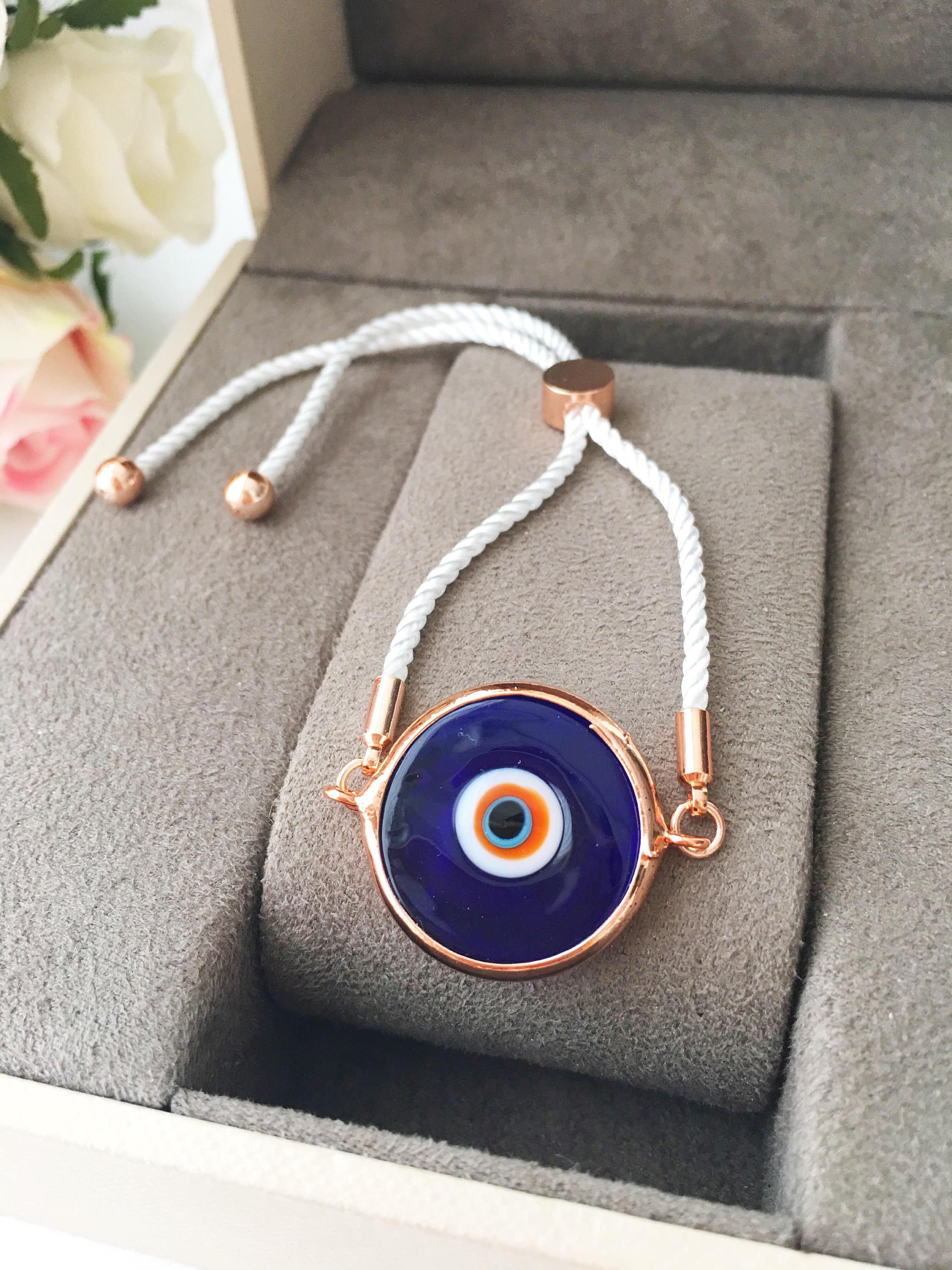 A beautiful blue evil eye bracelet made of Murano glass, featuring an adjustable black and white string, showcasing its unique charm and craftsmanship.