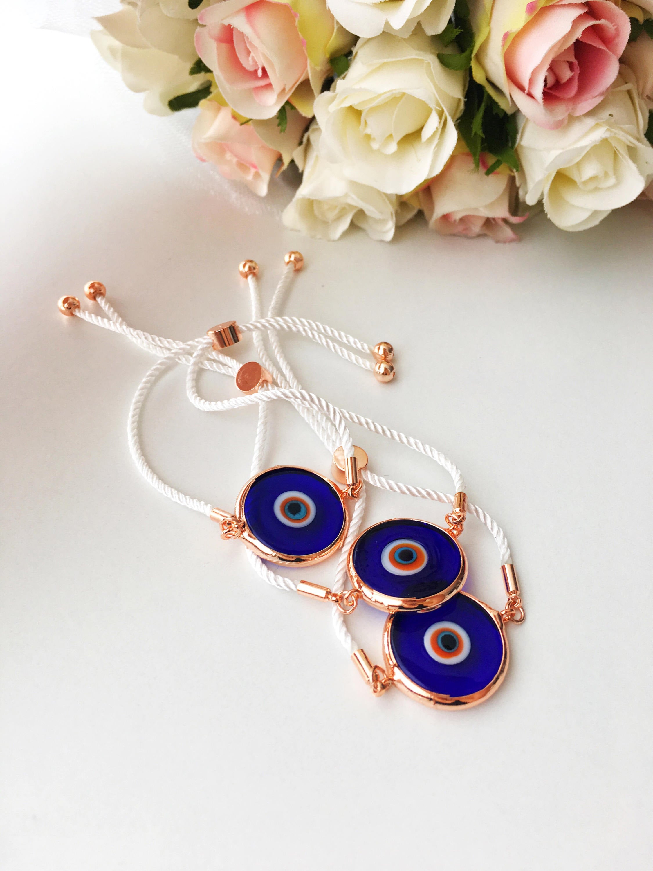 A beautiful blue evil eye bracelet made of Murano glass, featuring an adjustable black and white string, showcasing its unique charm and craftsmanship.