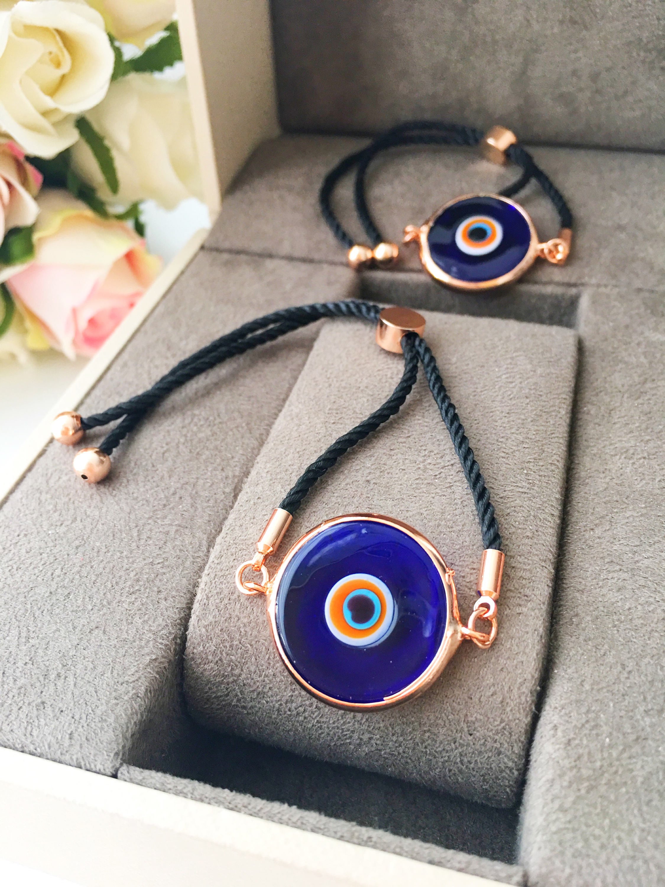 A beautiful blue evil eye bracelet made of Murano glass, featuring an adjustable black and white string, showcasing its unique charm and craftsmanship.