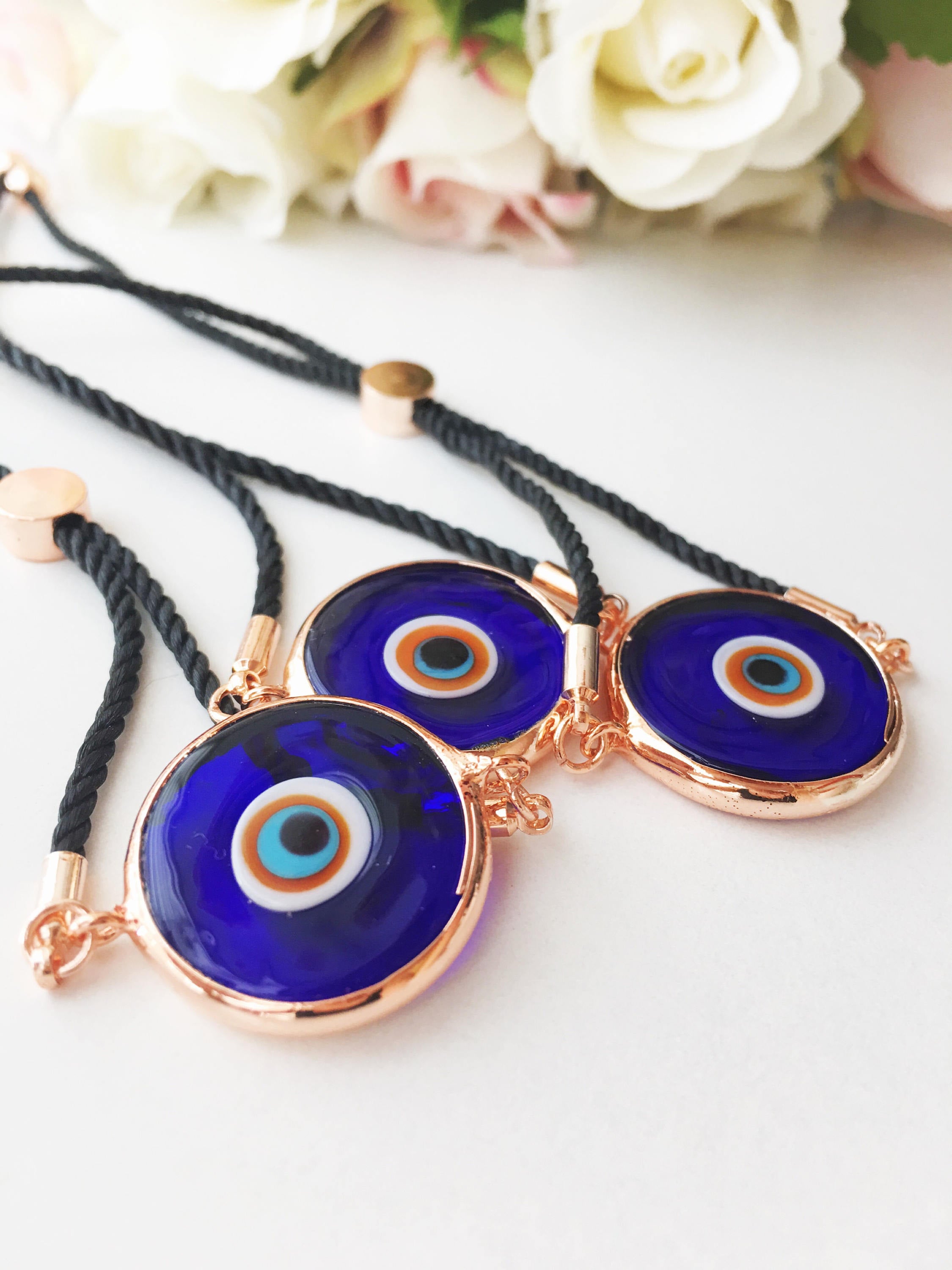 A beautiful blue evil eye bracelet made of Murano glass, featuring an adjustable black and white string, showcasing its unique charm and craftsmanship.