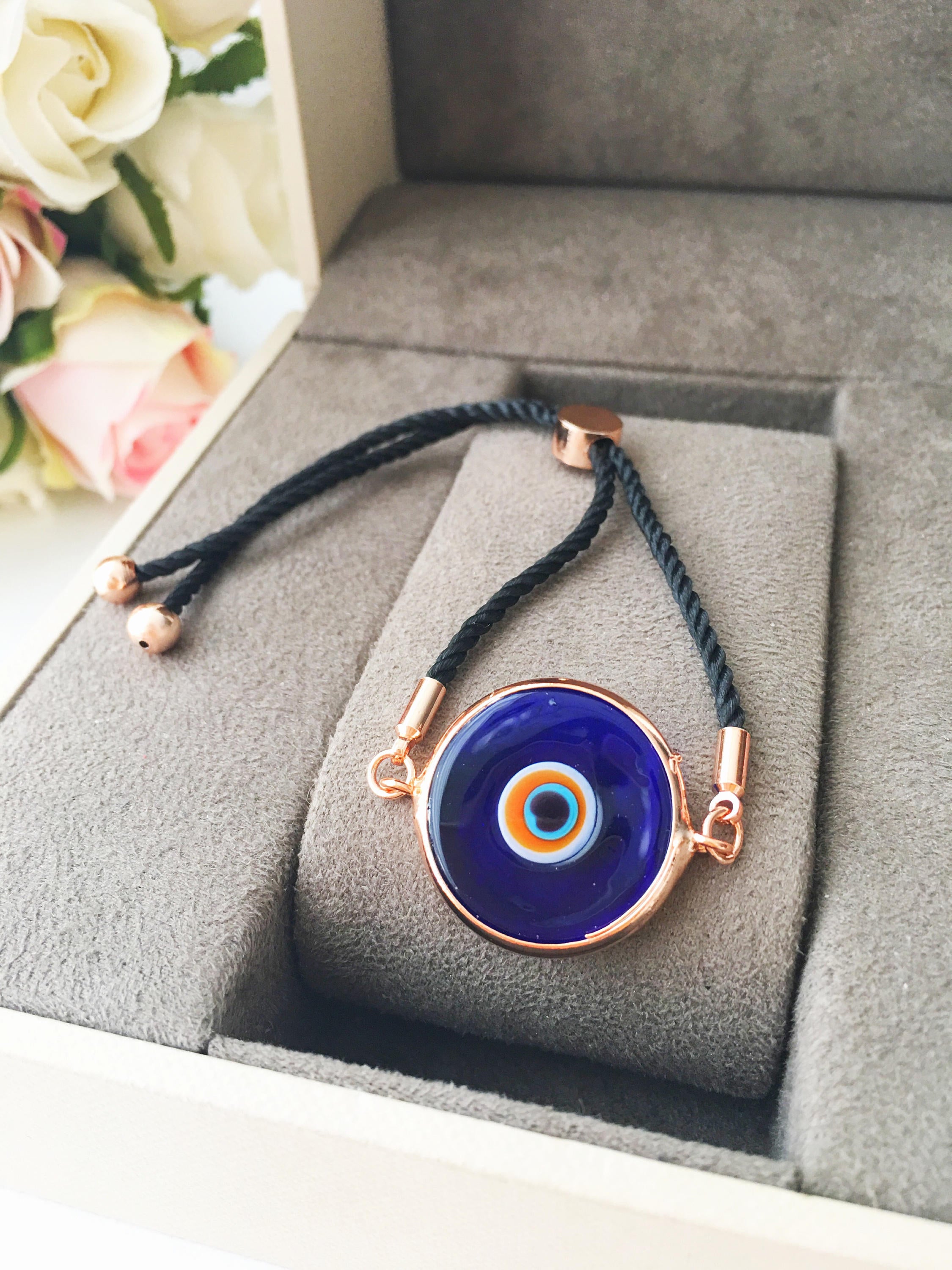 A beautiful blue evil eye bracelet made of Murano glass, featuring an adjustable black and white string, showcasing its unique charm and craftsmanship.