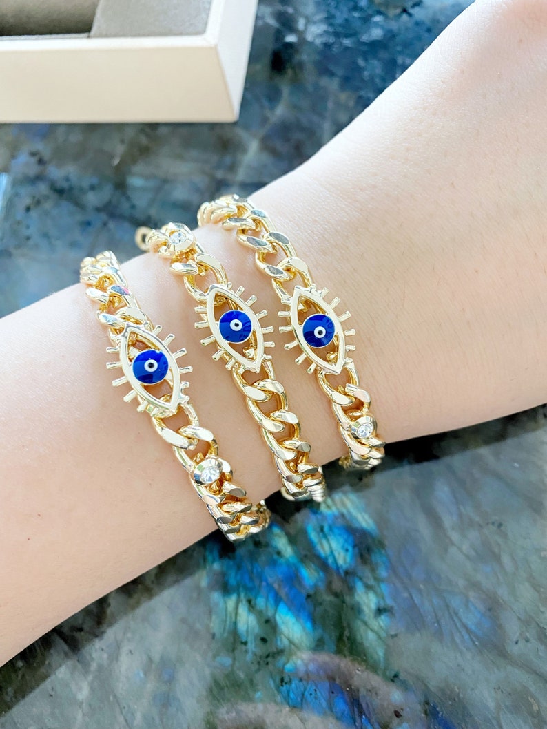 A stylish blue evil eye bracelet made of tarnish-resistant gold stainless steel, featuring a curb chain design and an adjustable fit.