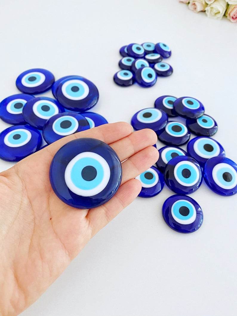 A collection of 10 blue glass evil eye beads without holes, showcasing various sizes from 3 to 5.5 cm, perfect for crafts and decorations.