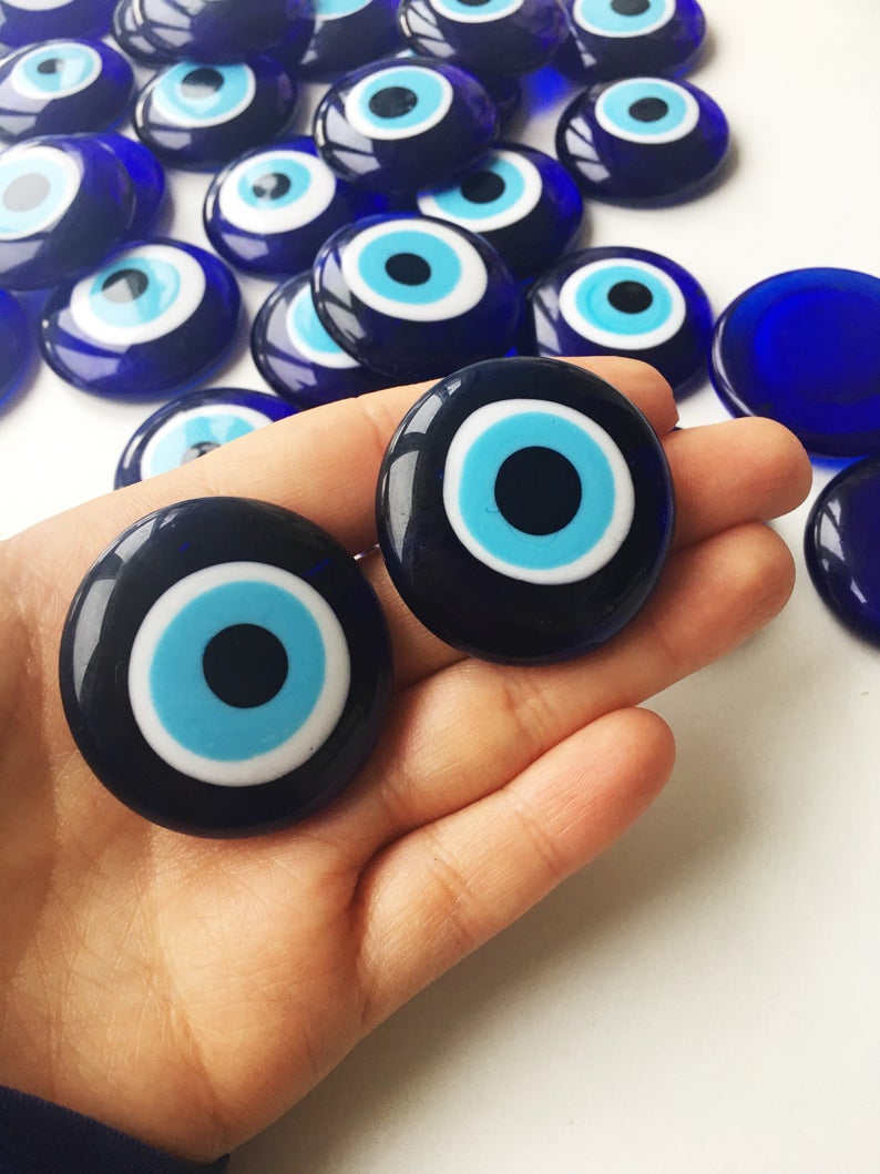 A collection of 10 blue glass evil eye beads without holes, showcasing various sizes from 3 to 5.5 cm, perfect for crafts and decorations.