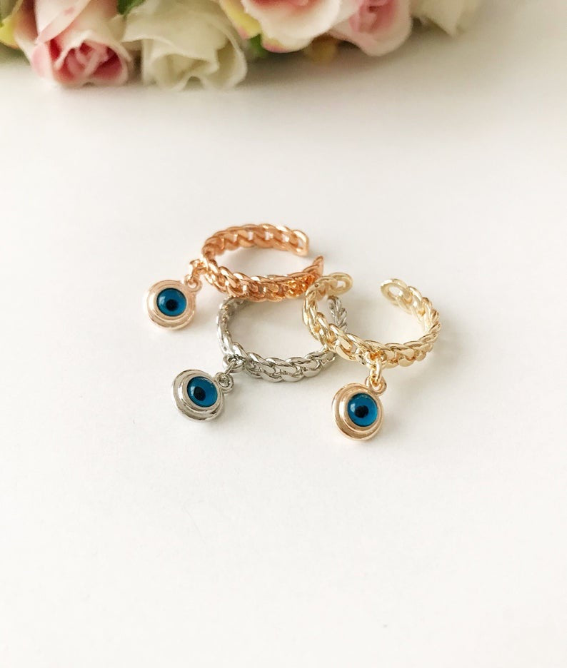 A stylish Blue Evil Eye Dangle Ring featuring a round blue evil eye bead, available in rose gold, silver, and gold finishes.