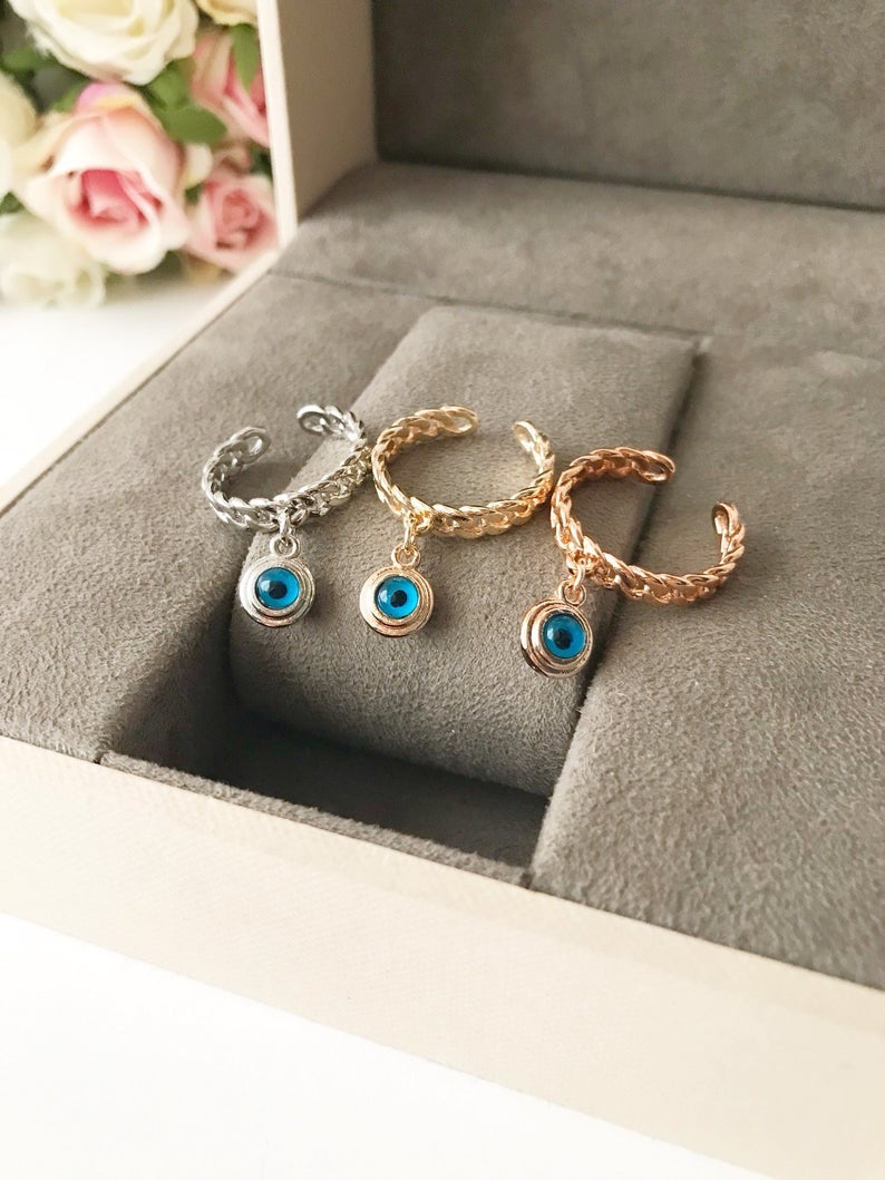 A stylish Blue Evil Eye Dangle Ring featuring a round blue evil eye bead, available in rose gold, silver, and gold finishes.