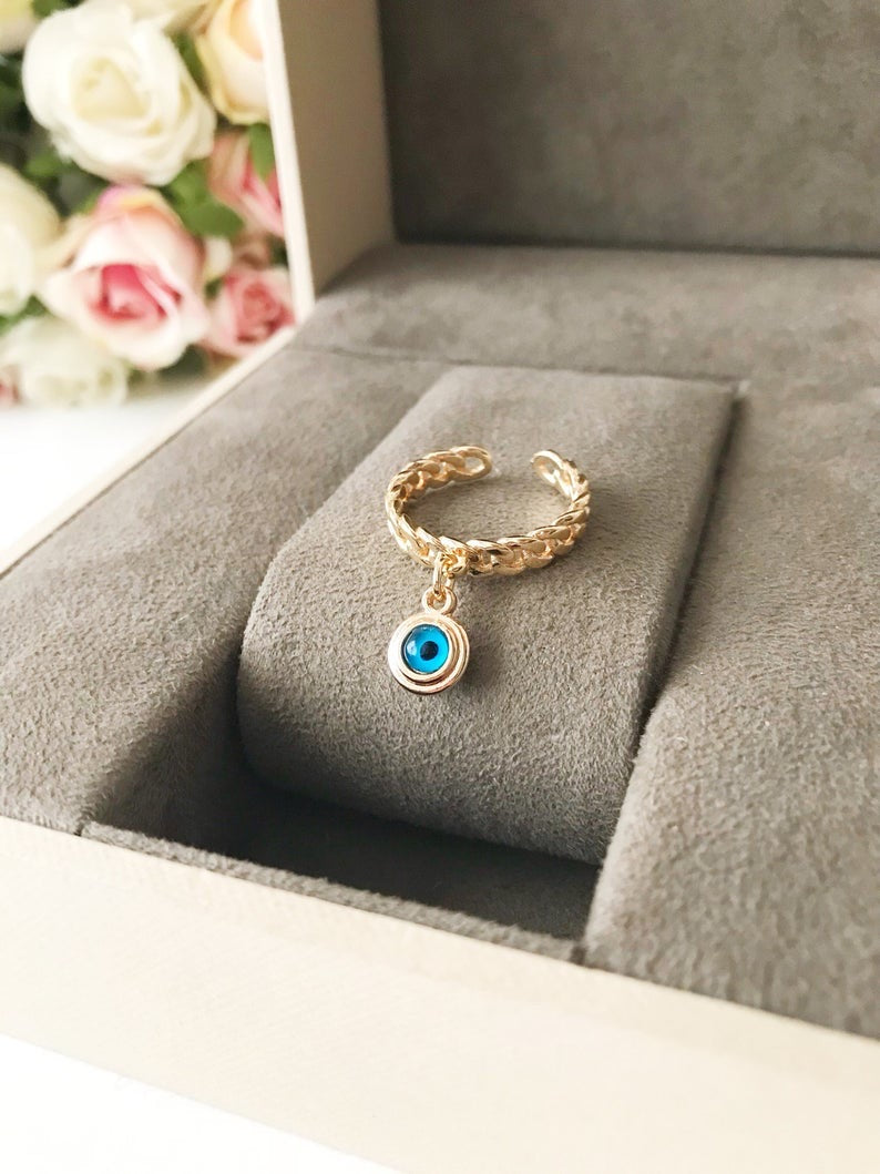 A stylish Blue Evil Eye Dangle Ring featuring a round blue evil eye bead, available in rose gold, silver, and gold finishes.