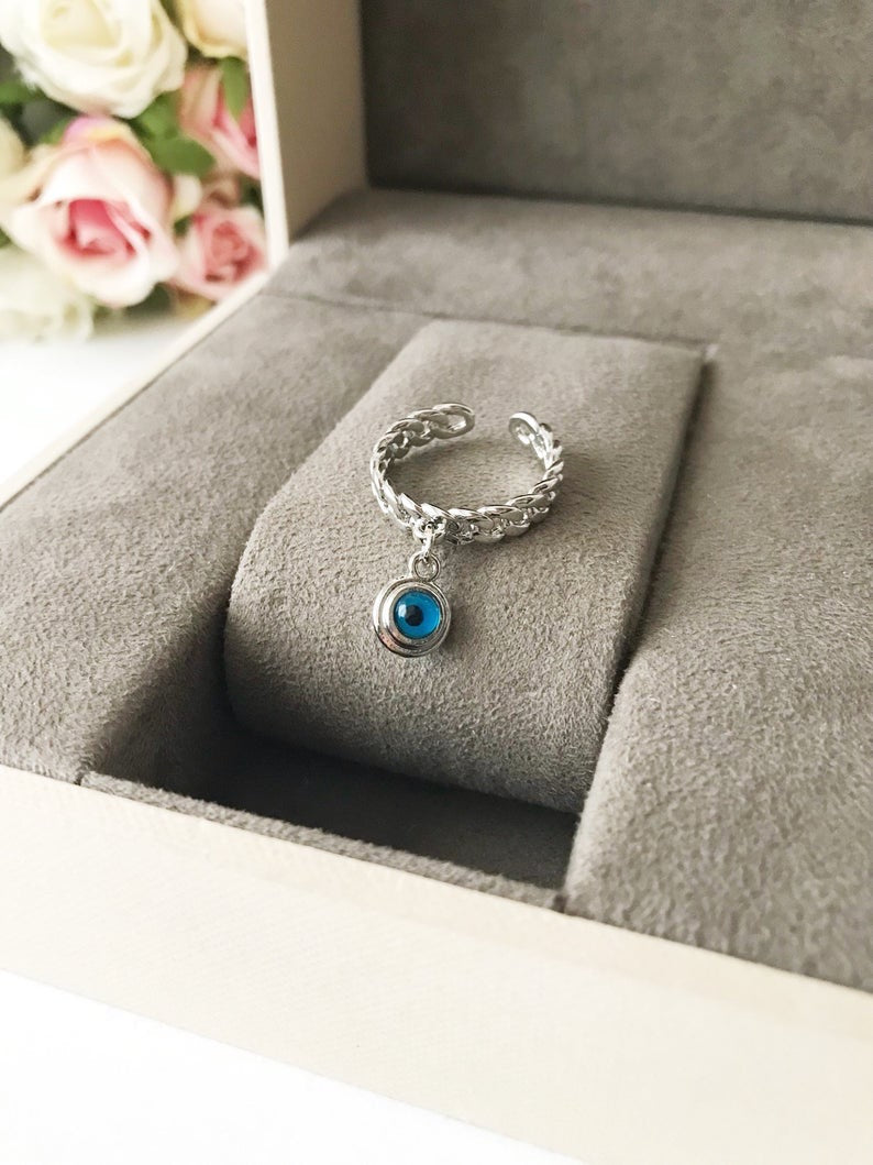 A stylish Blue Evil Eye Dangle Ring featuring a round blue evil eye bead, available in rose gold, silver, and gold finishes.