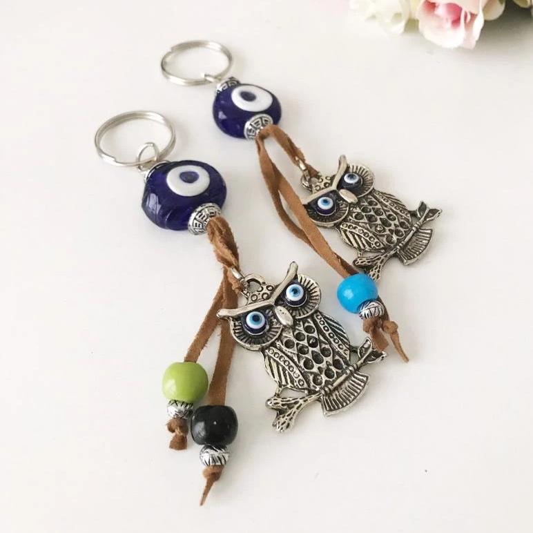 Blue evil eye good luck keychain featuring silver elephant and owl charms, perfect for keys or bags.