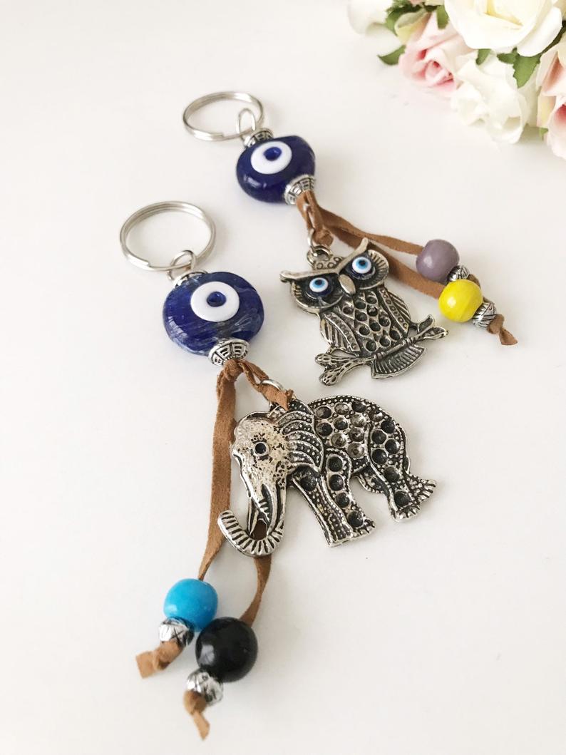 Blue evil eye good luck keychain featuring silver elephant and owl charms, perfect for keys or bags.