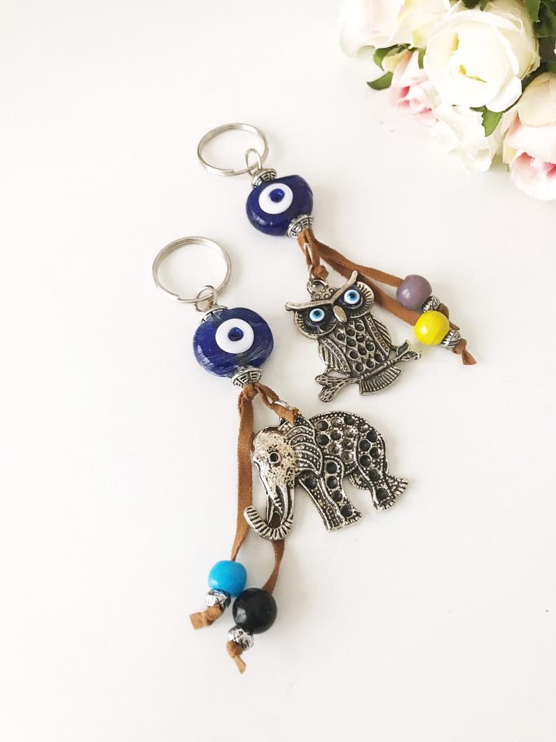 Blue evil eye good luck keychain featuring silver elephant and owl charms, perfect for keys or bags.