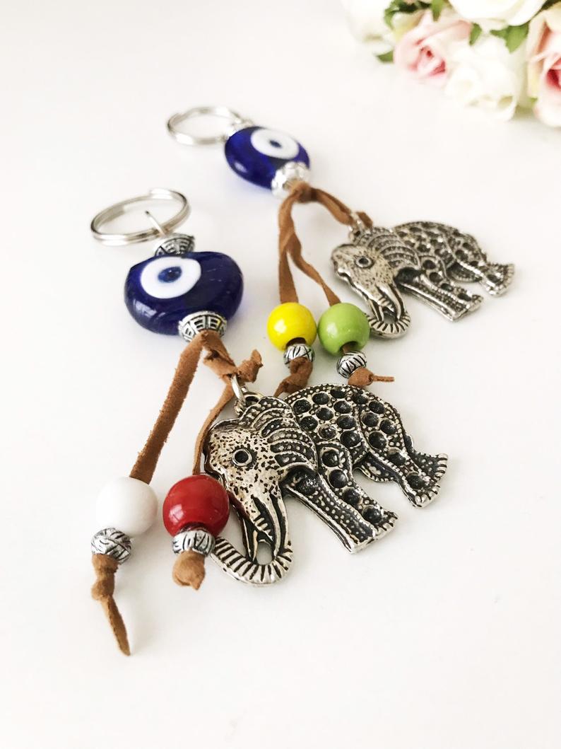 Blue evil eye good luck keychain featuring silver elephant and owl charms, perfect for keys or bags.