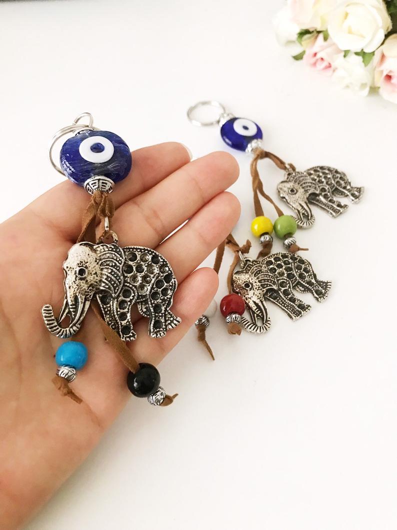 Blue evil eye good luck keychain featuring silver elephant and owl charms, perfect for keys or bags.