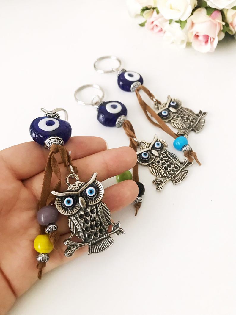 Blue evil eye good luck keychain featuring silver elephant and owl charms, perfect for keys or bags.