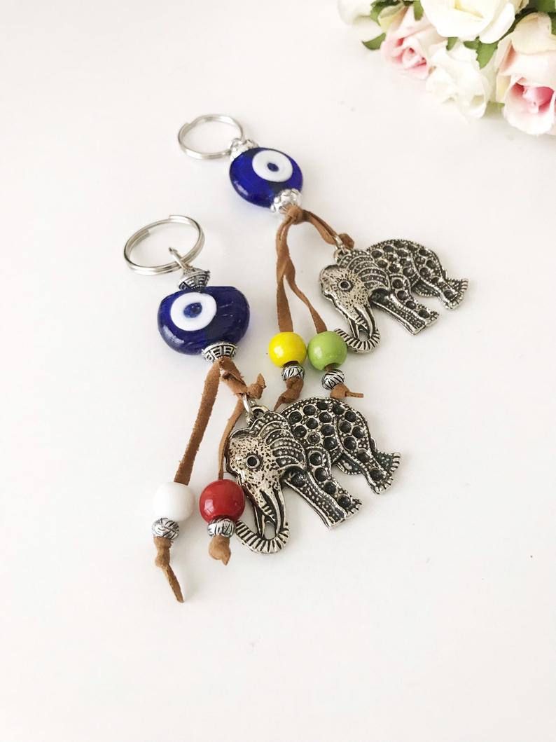 Blue evil eye good luck keychain featuring silver elephant and owl charms, perfect for keys or bags.