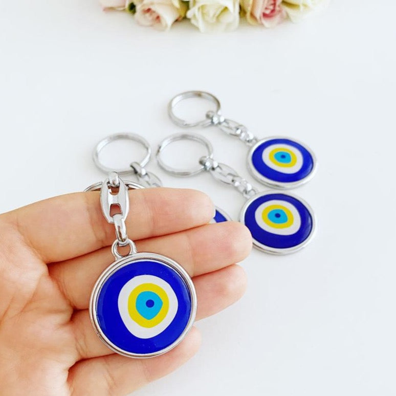 A stylish blue evil eye keychain made of enamel, featuring a minimalist silver design, symbolizing protection and good luck.