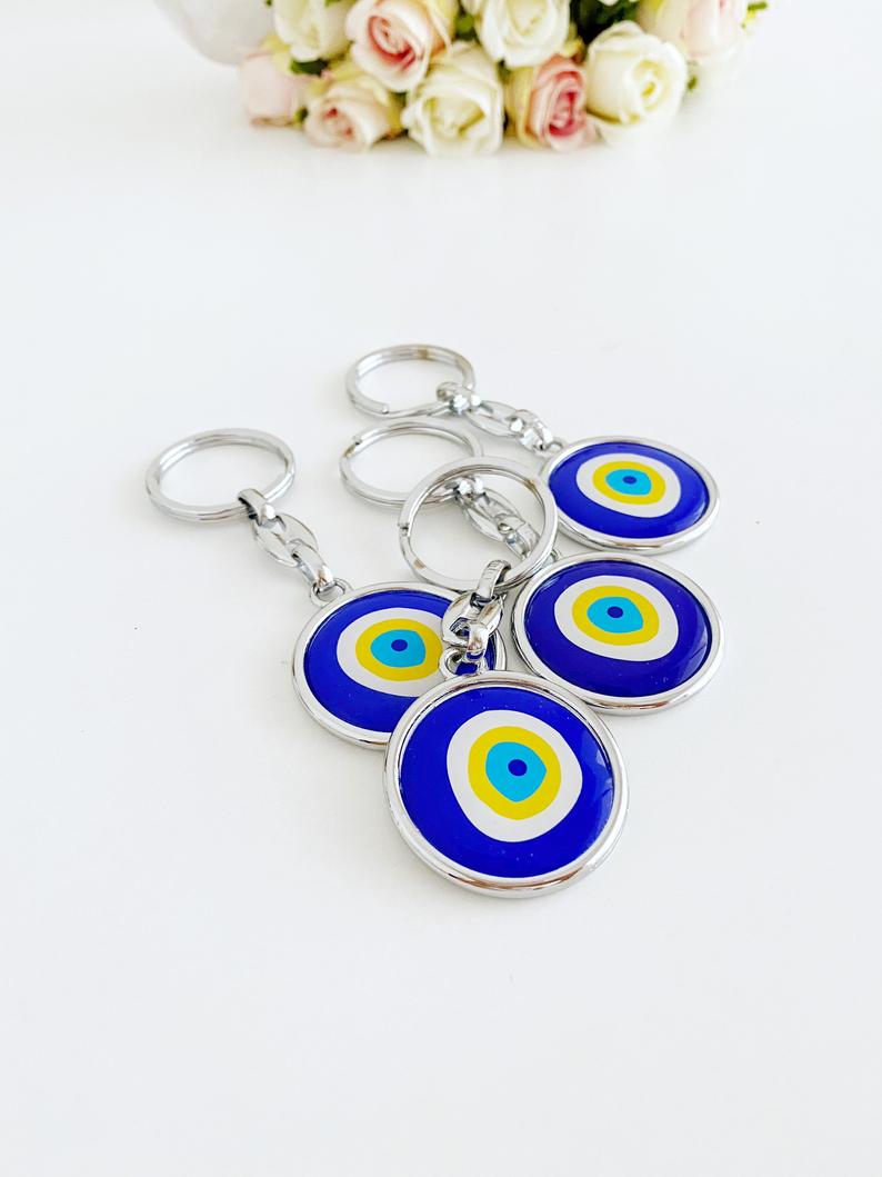 A stylish blue evil eye keychain made of enamel, featuring a minimalist silver design, symbolizing protection and good luck.