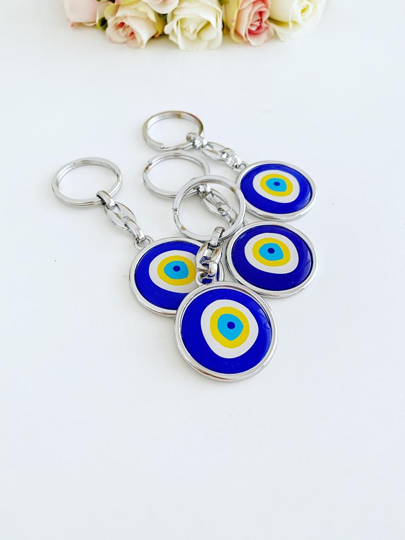 A stylish blue evil eye keychain made of enamel, featuring a minimalist silver design, symbolizing protection and good luck.