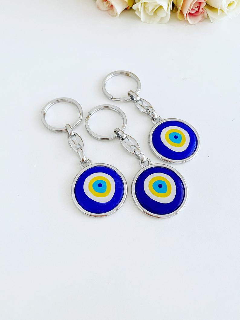 A stylish blue evil eye keychain made of enamel, featuring a minimalist silver design, symbolizing protection and good luck.