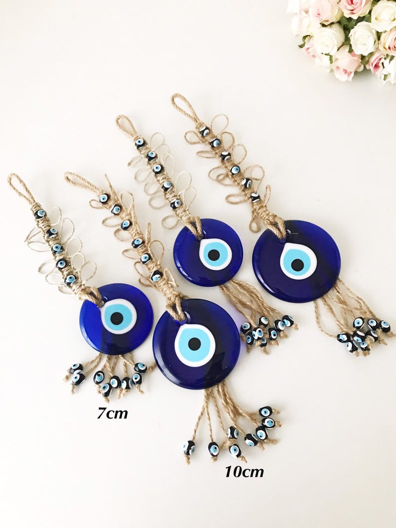 Handmade blue evil eye macrame wall hanging featuring a large evil eye bead and tiny blue beads, perfect for home decor.